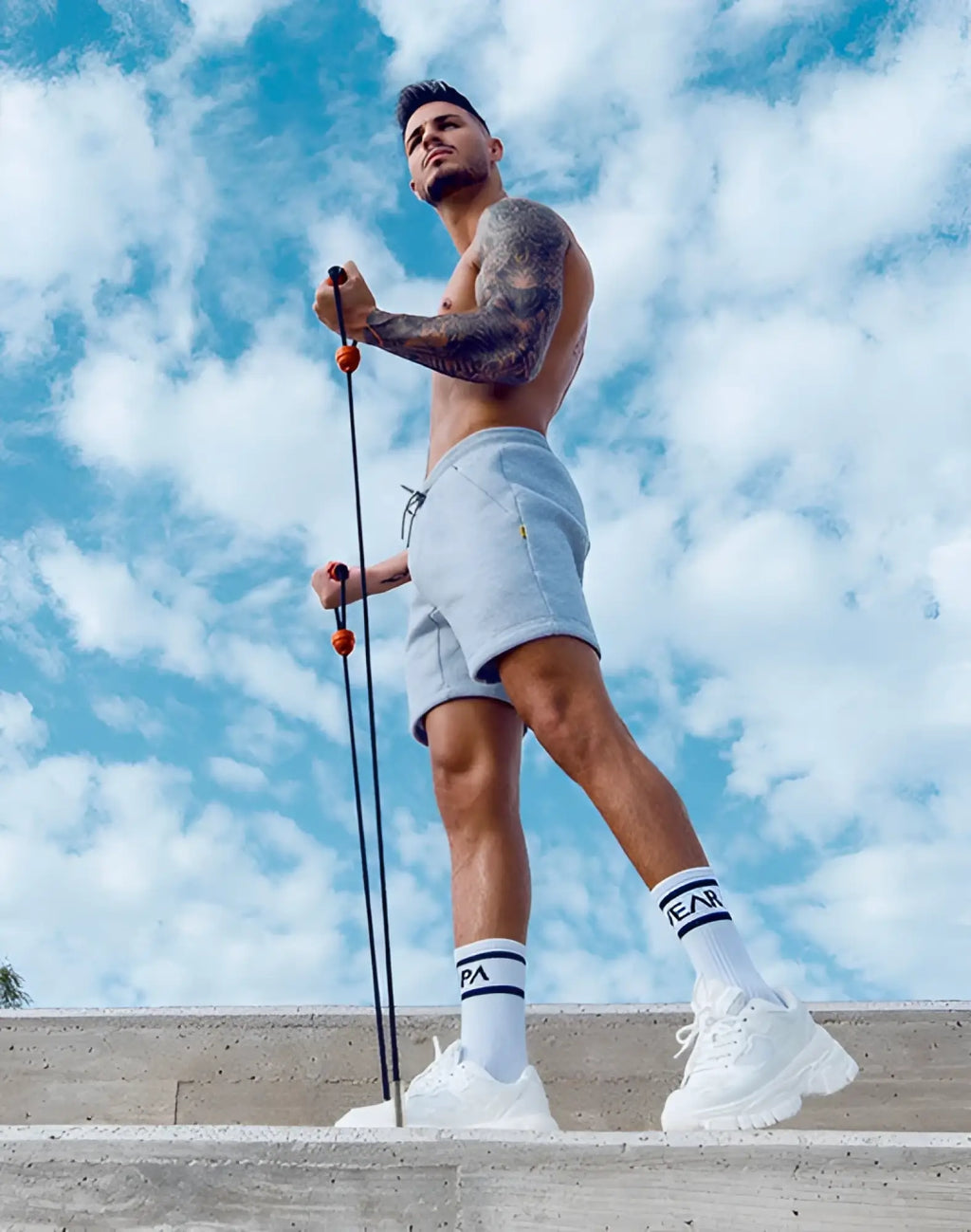 A man outdoors wearing supawear recovery shorts grey marle with light gray athletic shorts and holding a resistance band