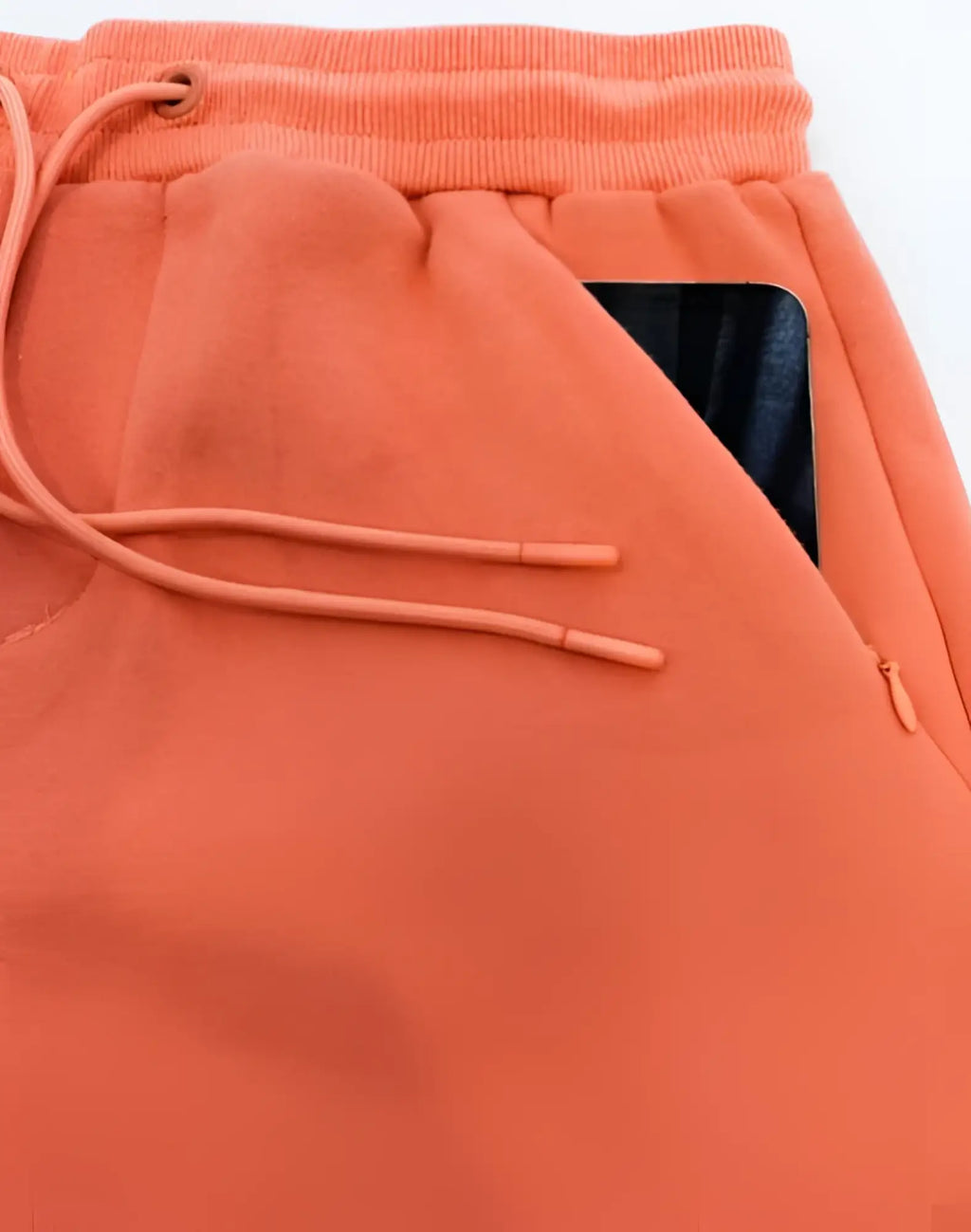 Orange fleece supawear recovery shorts with drawstring waistband and zippered side pocket holding a black smartphone
