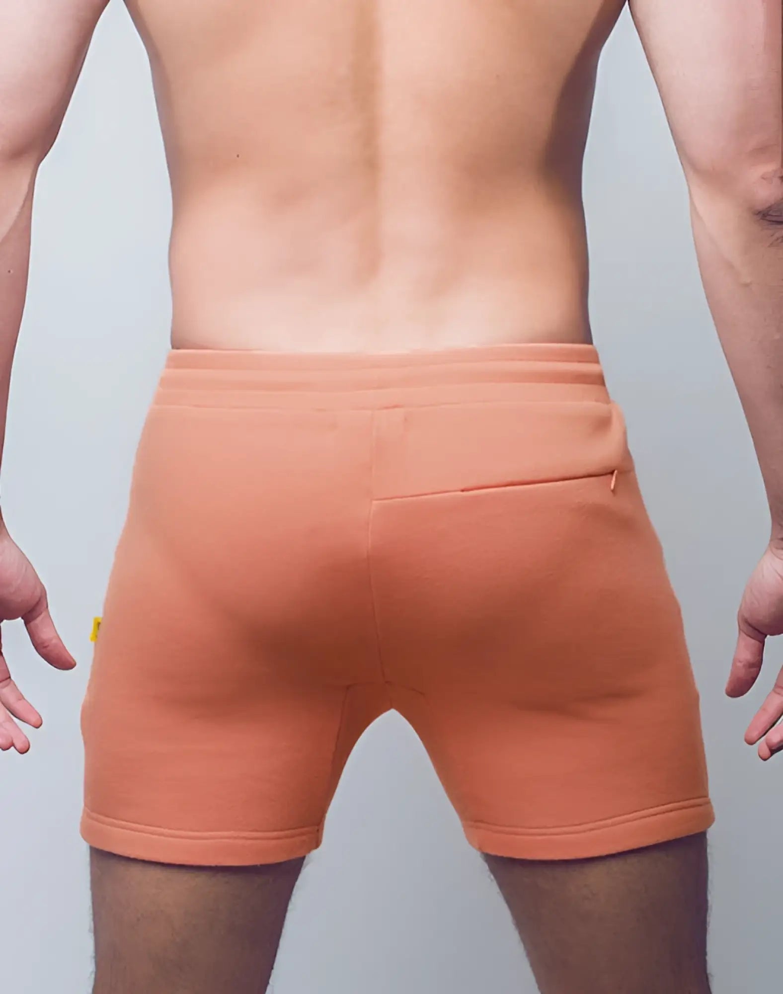 Orange textured fabric supawear recovery shorts with ribbed waistband and back pocket shown from the back side
