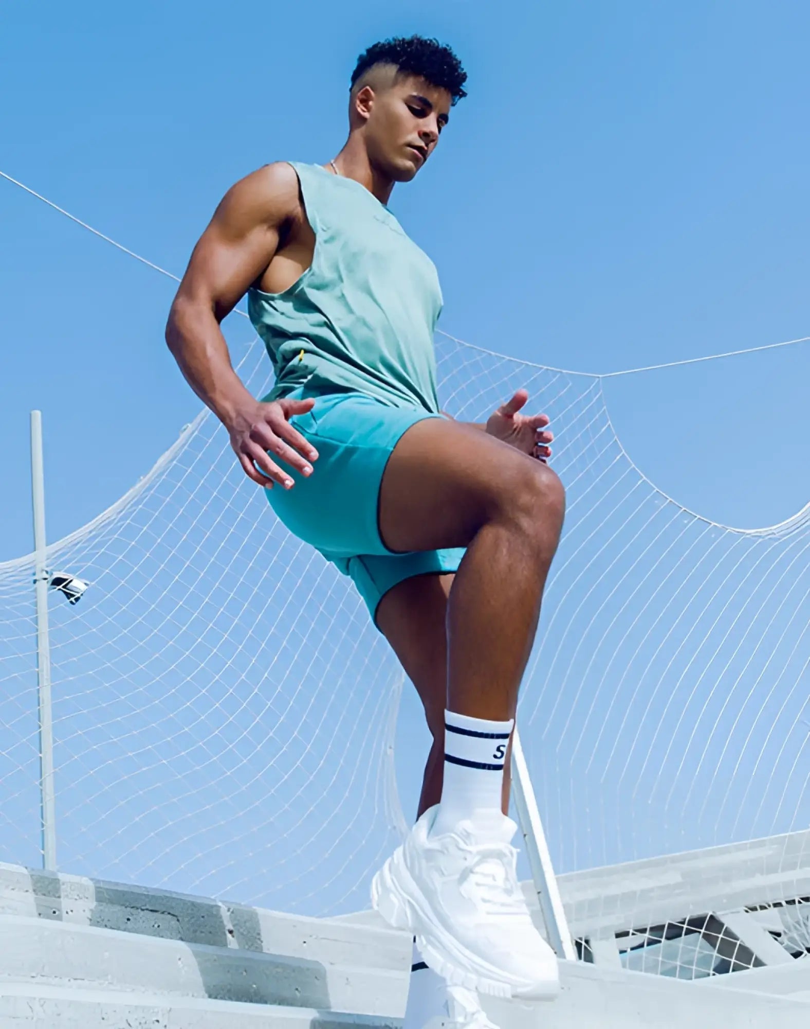 White chunky sneakers with thick soles and laces paired with green supawear recovery shorts reboot green