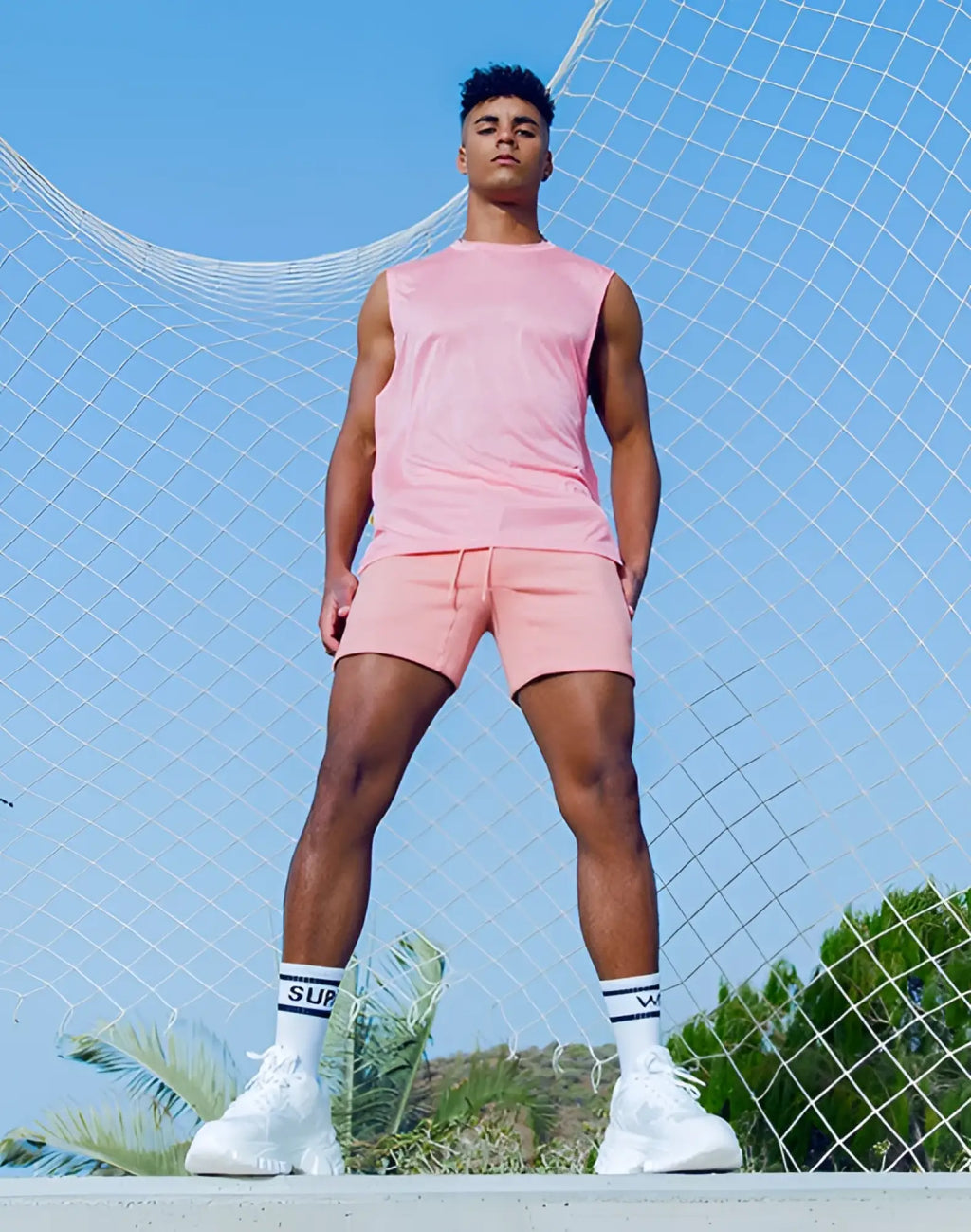 A man wearing a pink sleeveless tank and matching shorts in the supawear recovery tank reboot clay set