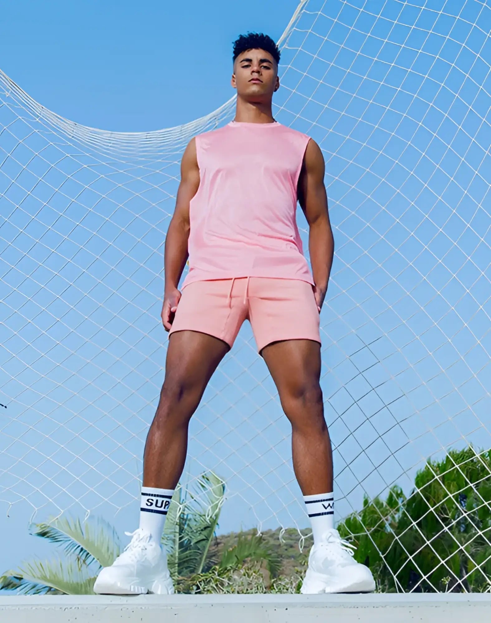 A man wearing a pink sleeveless tank and matching shorts in the supawear recovery tank reboot clay set