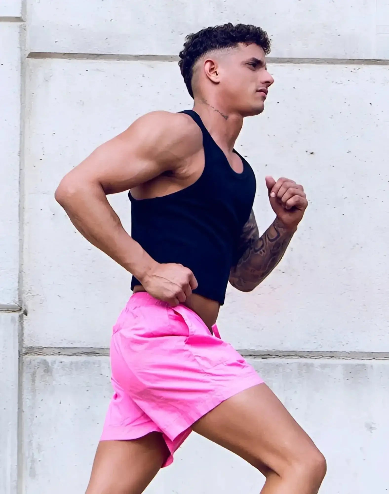 Bright pink athletic shorts with a simple clean design and no branding paired with supawear ribbed cropped singlet black