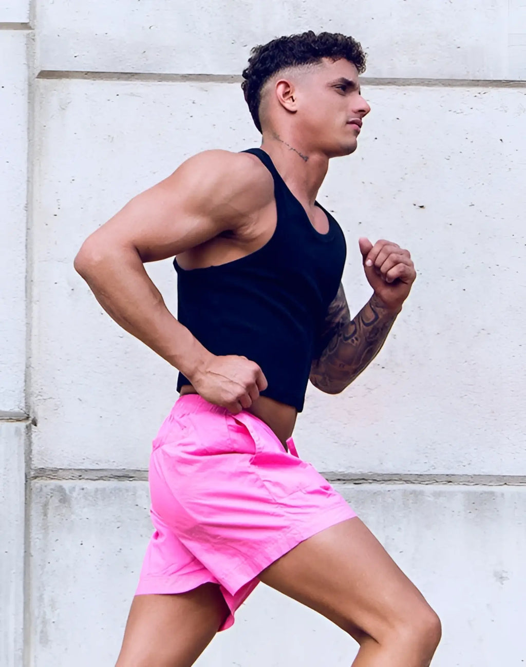 Bright pink athletic shorts with a simple clean design and no branding paired with supawear ribbed cropped singlet black