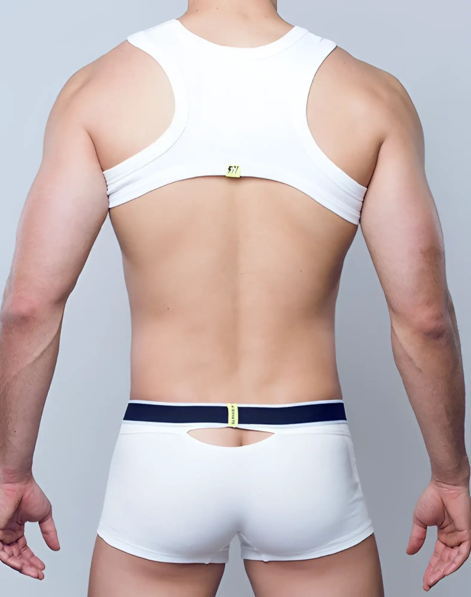 Back side of supawear ribbed slashed cropped top in white with navy belt detail and small yellow logo on the back