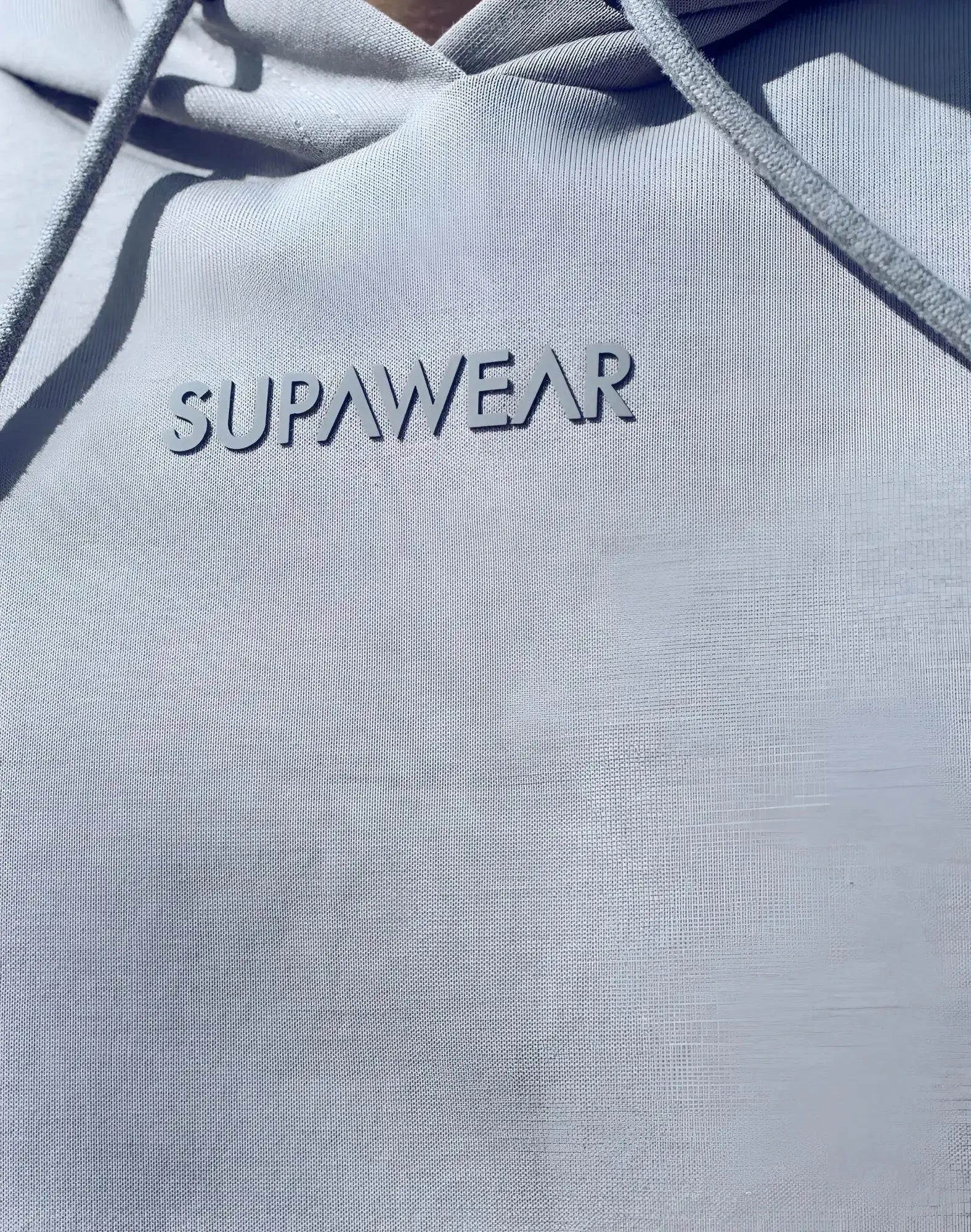 Light gray supawear sleeveless hoodie with subtle textured fabric and matching drawstrings for casual wear