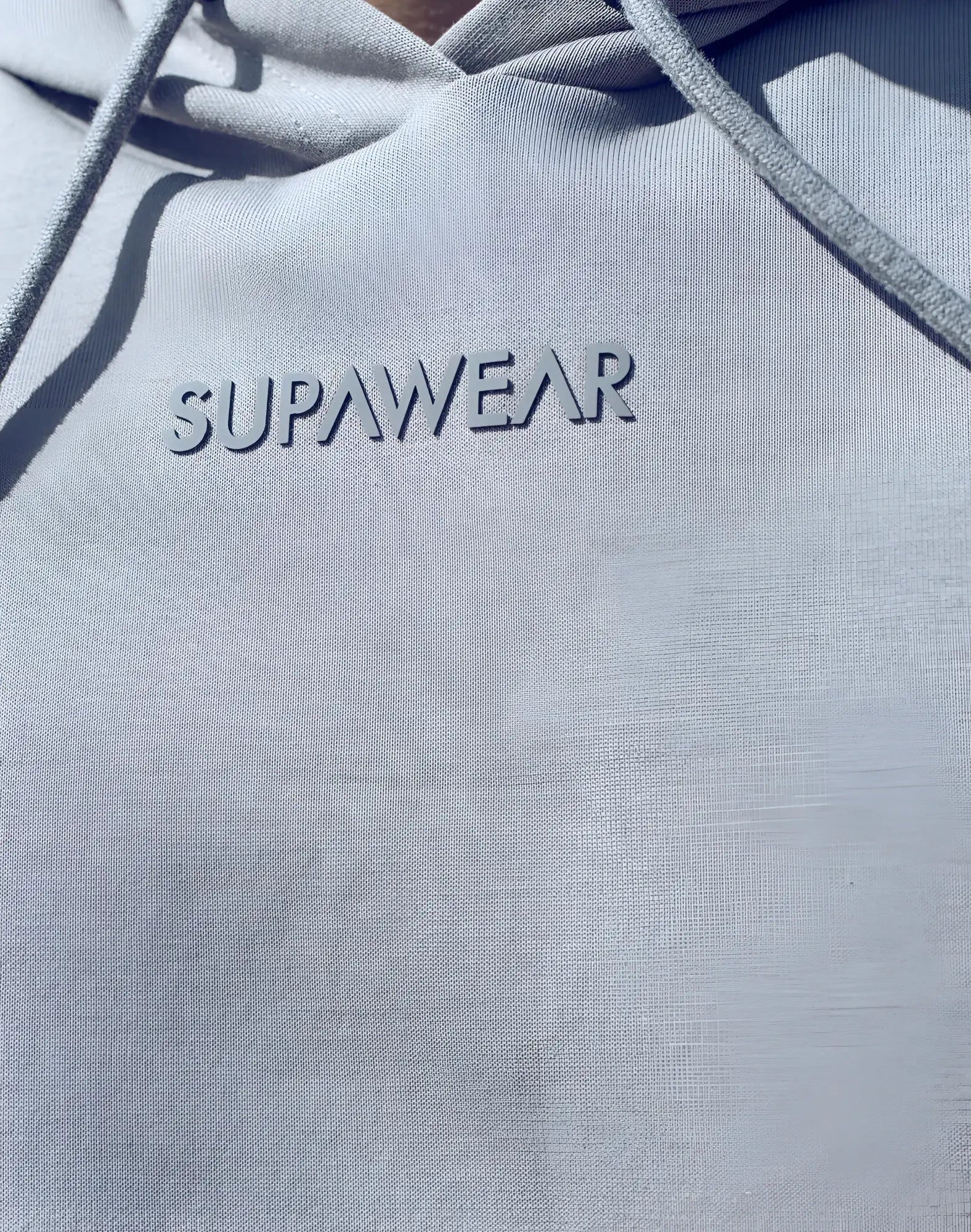 Light gray supawear sleeveless hoodie with subtle textured fabric and matching drawstrings for casual wear