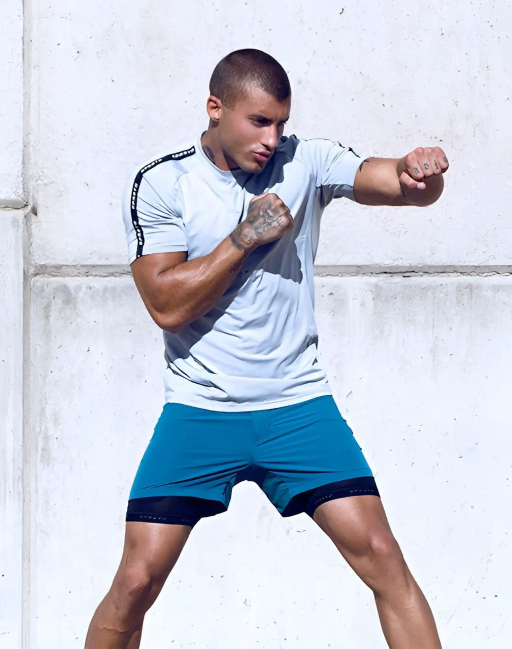 A man wearing a supawear SPR fit tee pale grey in light gray with black trim and teal shorts for athletic use