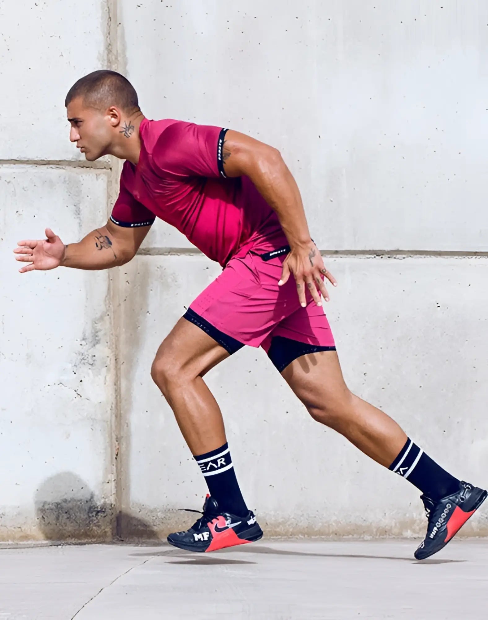 A man in motion wearing a supawear spr flex tee redbud in vibrant pink with black trim paired with dark blue sneakers