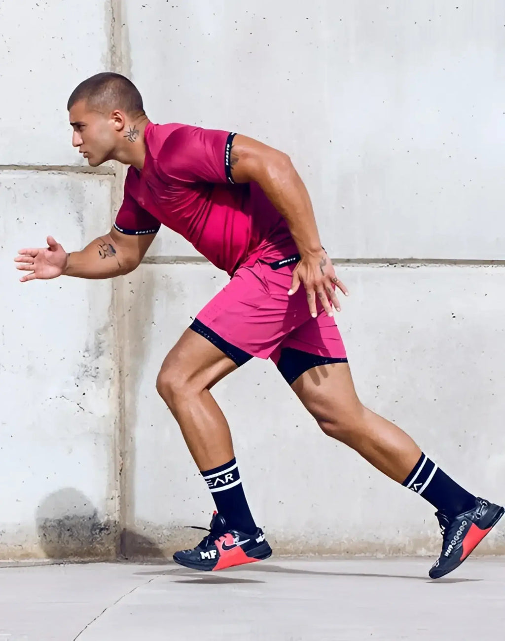 A man in motion wearing a supawear spr flex tee redbud in vibrant pink with black trim paired with dark blue sneakers