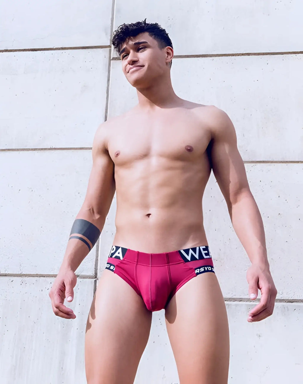 A man wearing supawear SPR Max brief underwear in vibrant redbud with black and white branded waistband