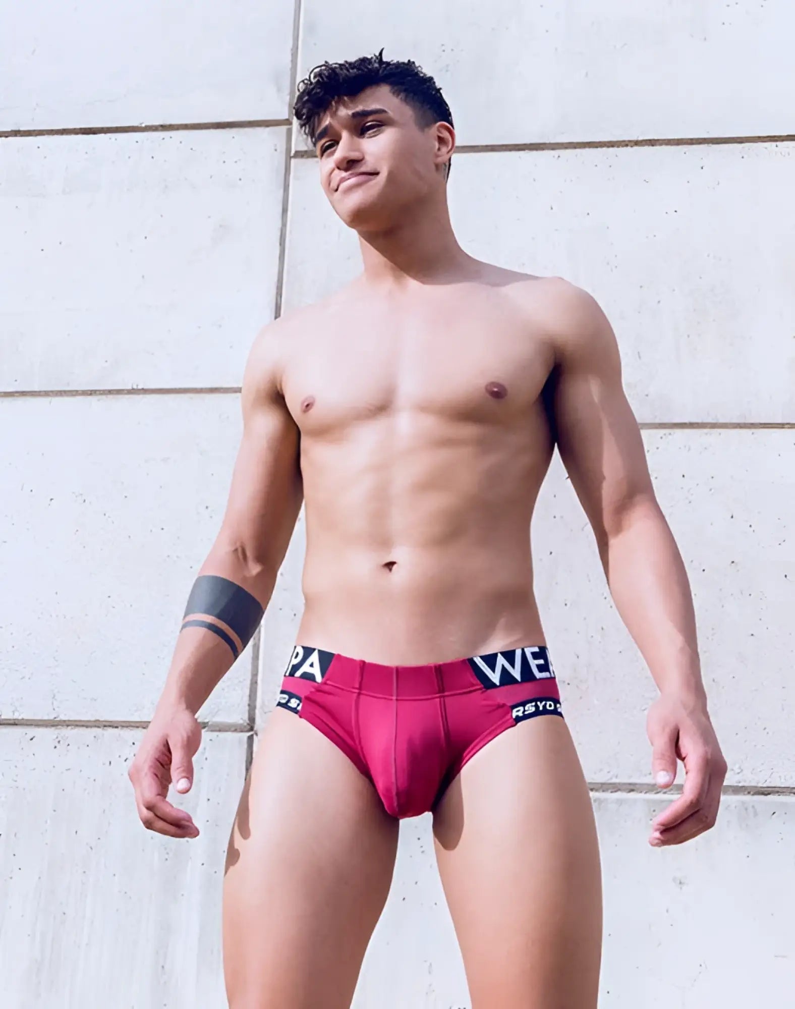 A man wearing supawear SPR Max brief underwear in vibrant redbud with black and white branded waistband