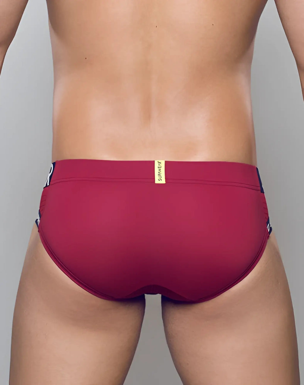 SupaWear SPR max brief underwear in redbud maroon with black side panels and a gold brand tag for swim use
