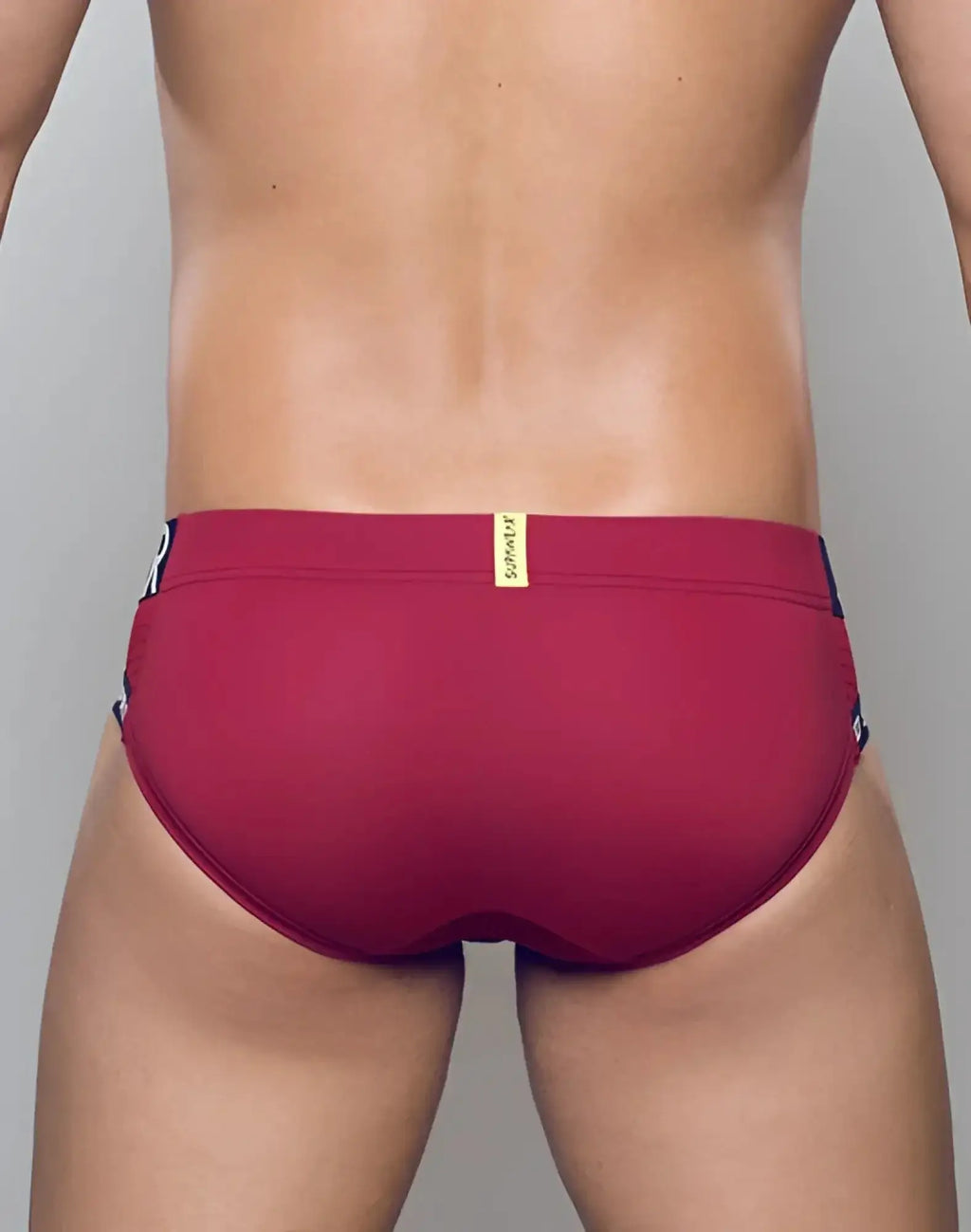 SupaWear SPR max brief underwear in redbud maroon with black side panels and a gold brand tag for swim use