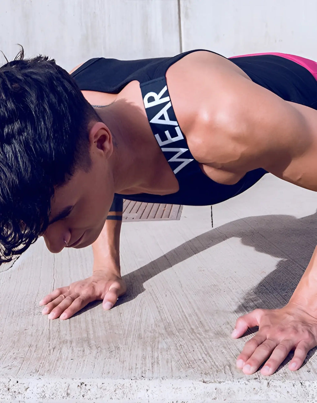 Black and pink SUPAWEAR SPR Max Singlet athletic tank top with white wear lettering on the strap for workout use