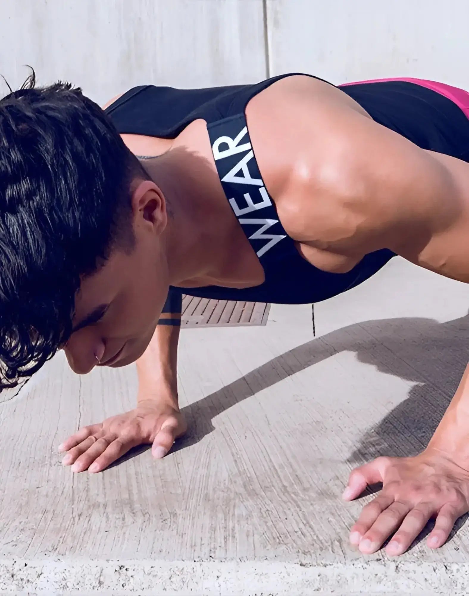 Black and pink SUPAWEAR SPR Max Singlet athletic tank top with white wear lettering on the strap for workout use