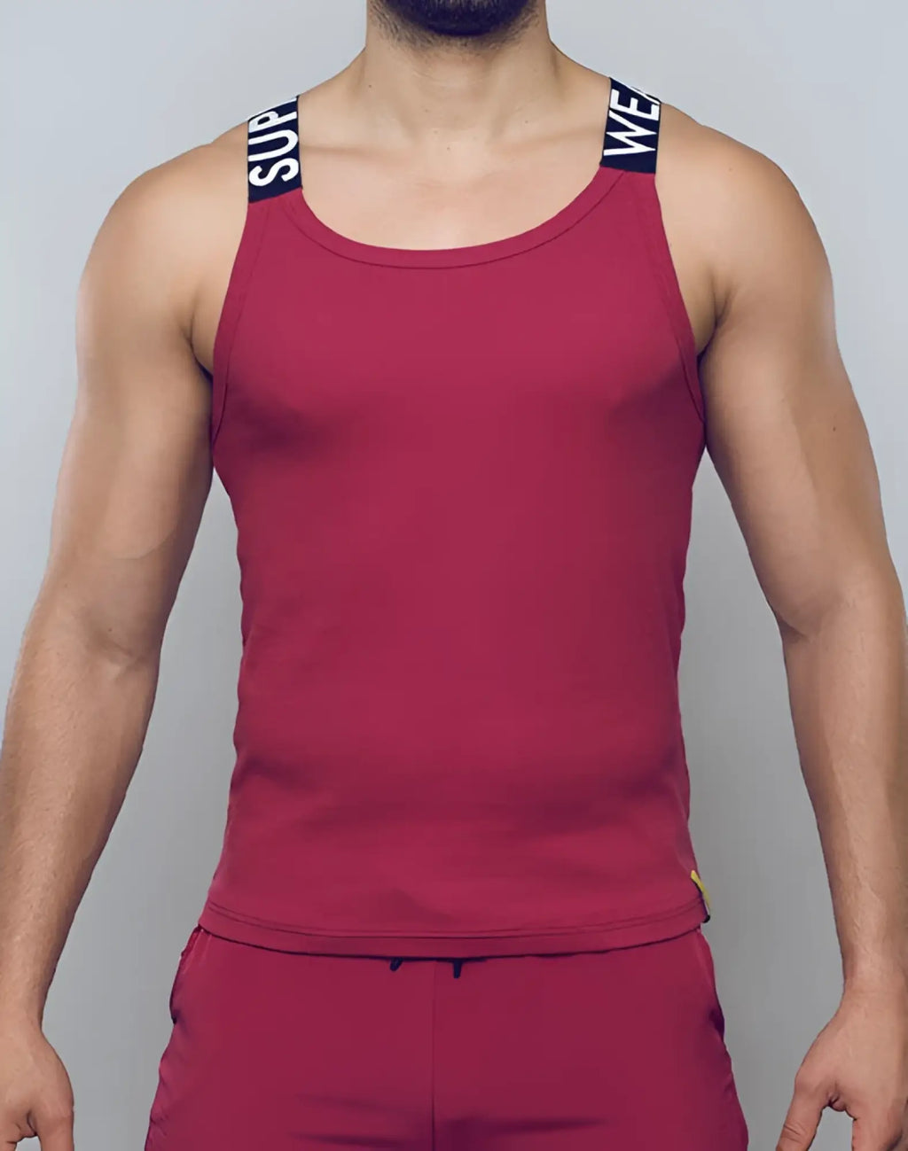 Red ribbed tank top with black shoulder straps and white lettering from SUPAWEAR SPR Max Singlet Redbud collection