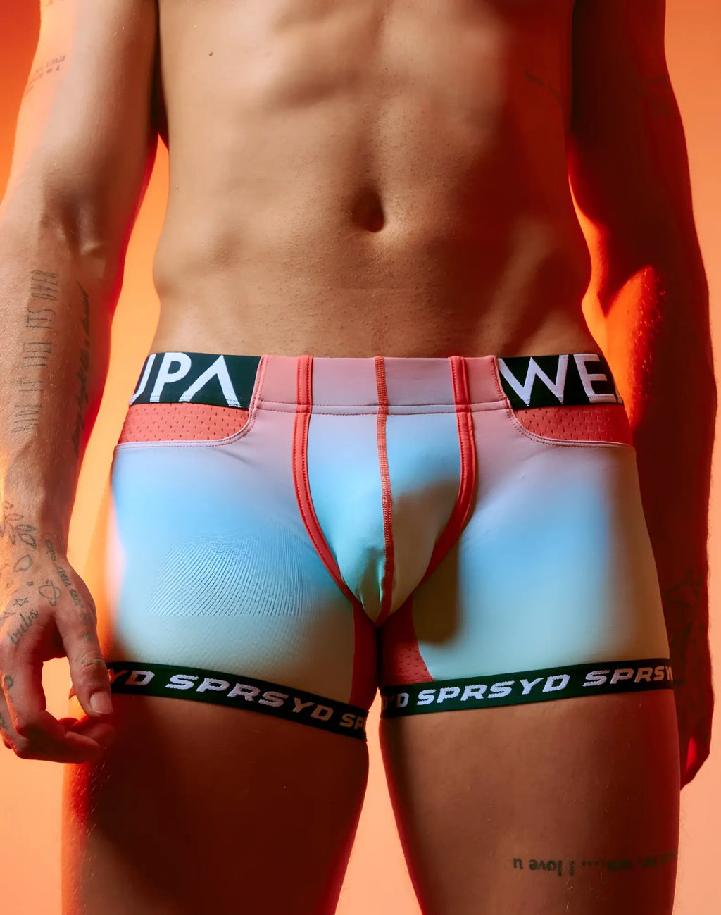 Pastel gradient blue and pink SUPAWEAR SPR performance athletic briefs with red trim and black sprsyd waistband and leg bands