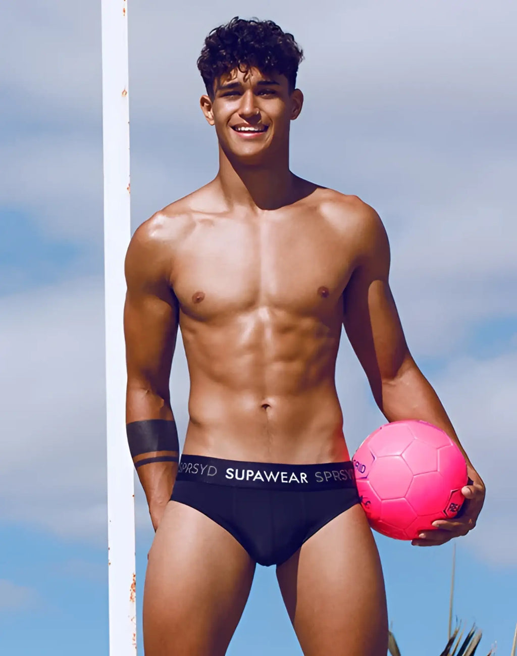 SupaweAR spr pro brief underwear in black displayed with a pink soccer ball featuring black hexagonal panels and white stitching