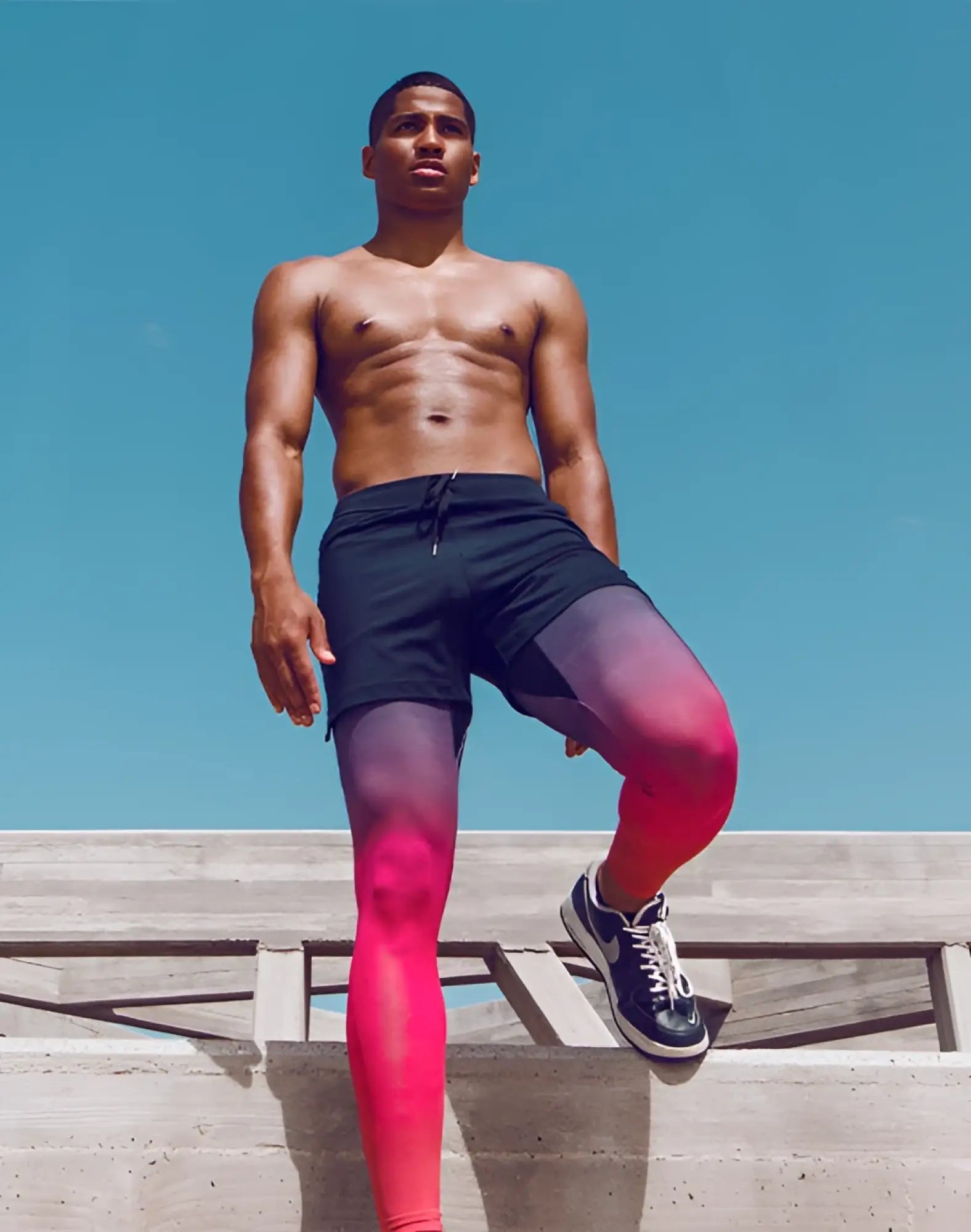 Black athletic shorts with drawstring waistband paired with gradient pink to purple SUPAWEAR SPR training tights red