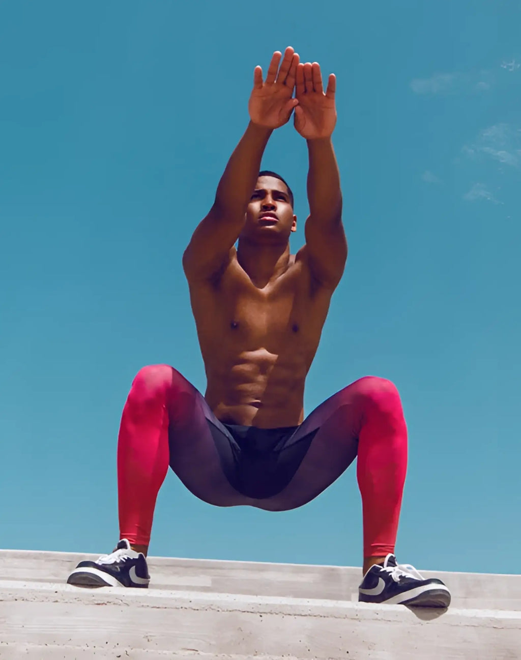 A man wearing supawear SPR training tights in red with a red and black gradient paired with white Nike sneakers