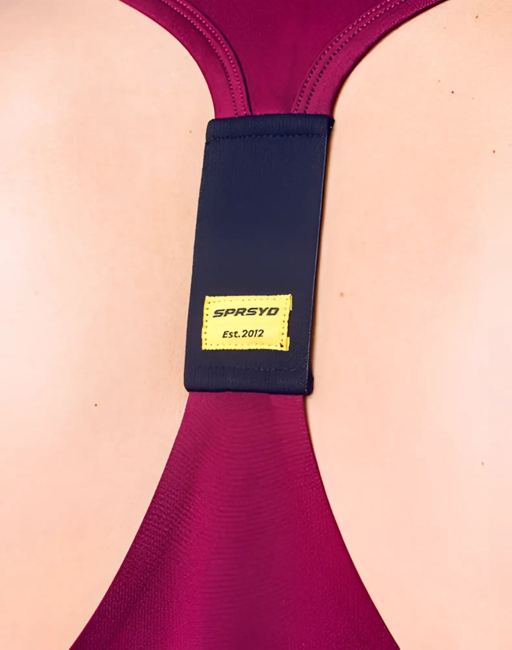 A navy blue elastic band with a yellow label showing sprsyd and est for SUPAWEAR spr y-tank deep purple