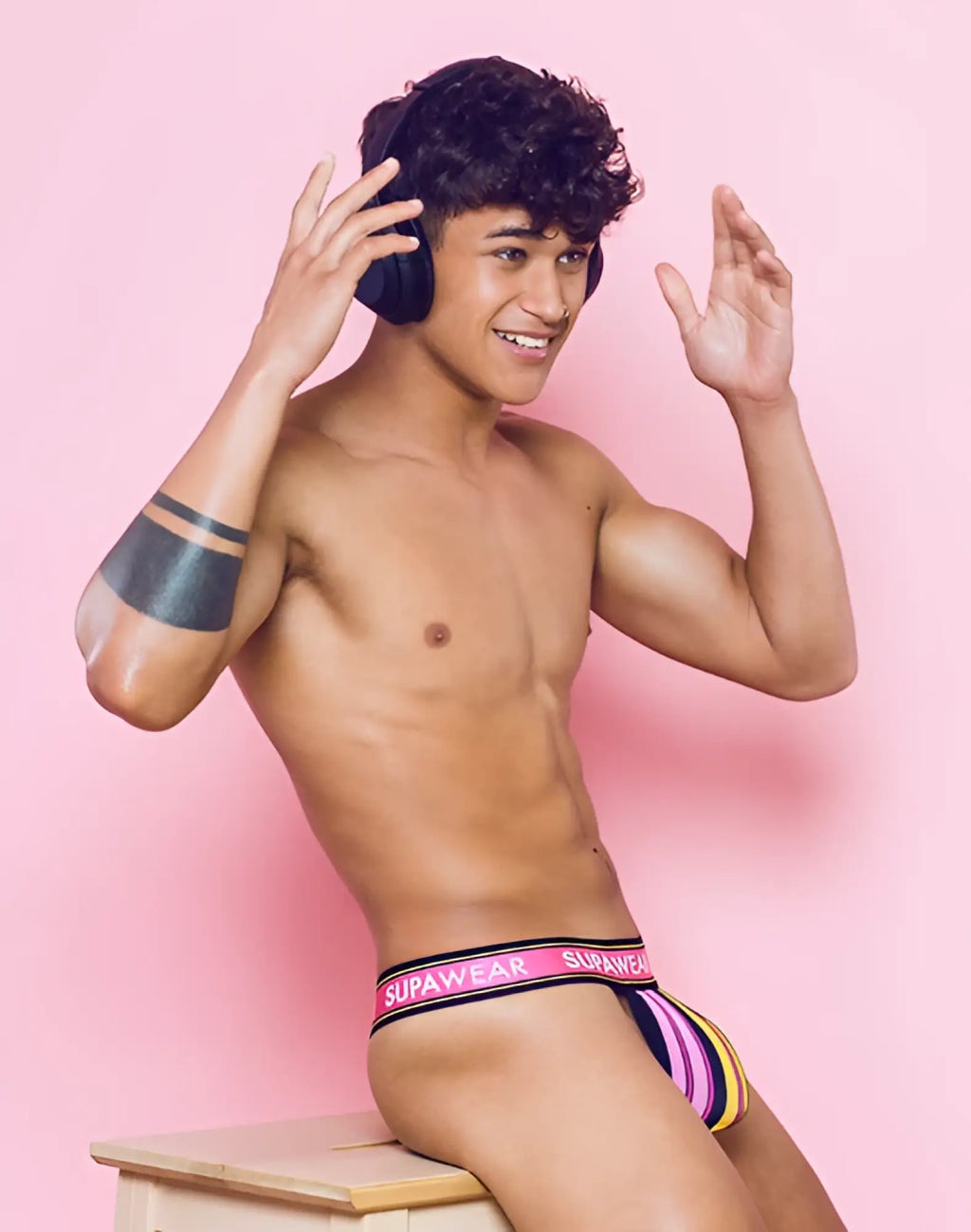 SupaWear sprint thong underwear with vibrant purple yellow and black stripes and a pink waistband front view