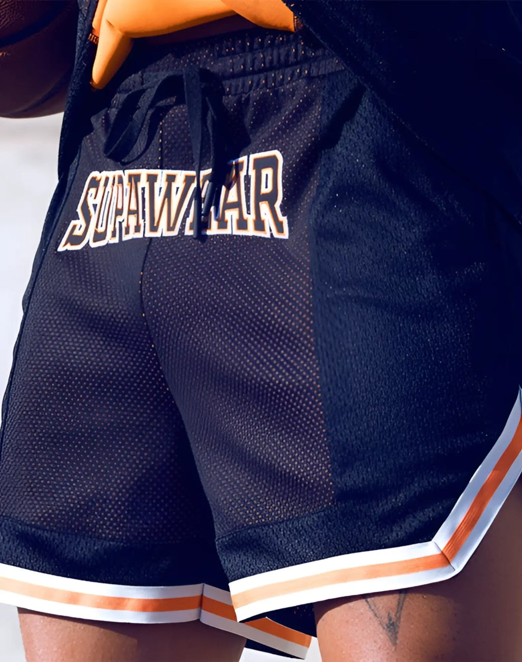 Back view of supawear swish mesh basketball shorts in neon orange with sunwarr lettering and striped hem