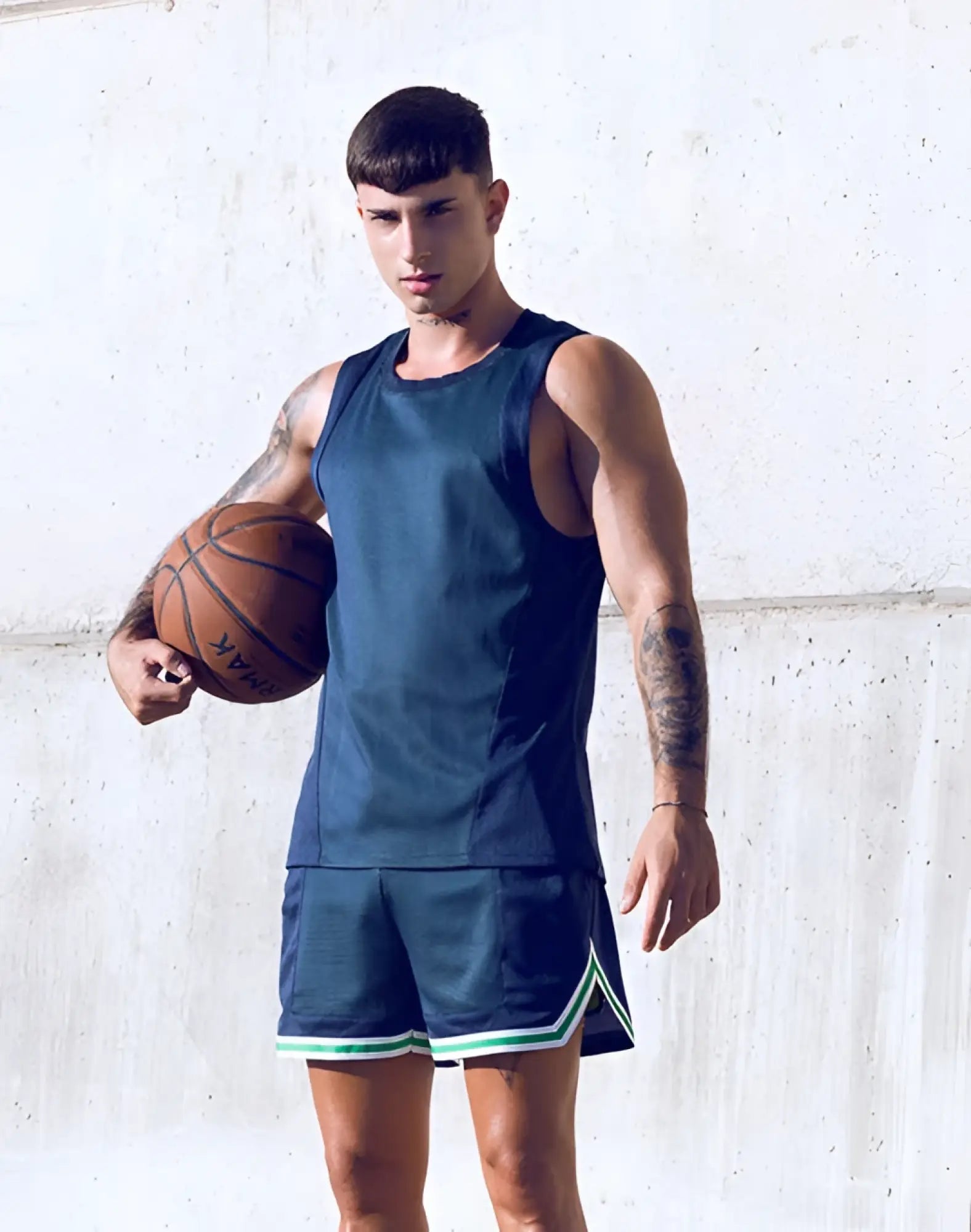 A man wearing a supawear swish mesh singlet in neon green with navy blue mesh basketball shorts trimmed in green and white