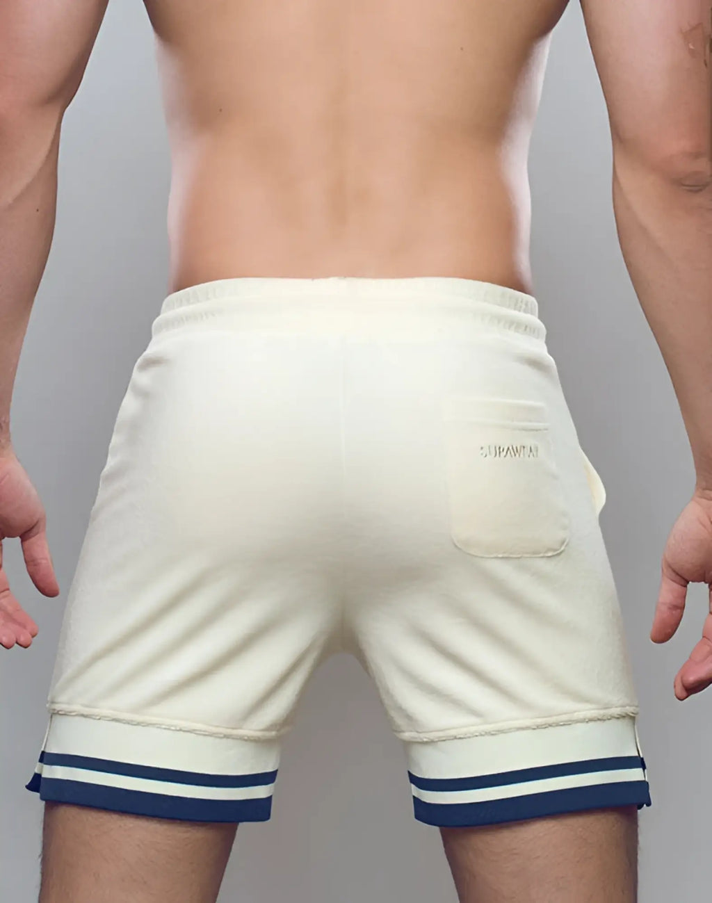 Cream-colored SUPAWEAR terry towelling shorts with navy white striped cuffs and branded patch on back pocket