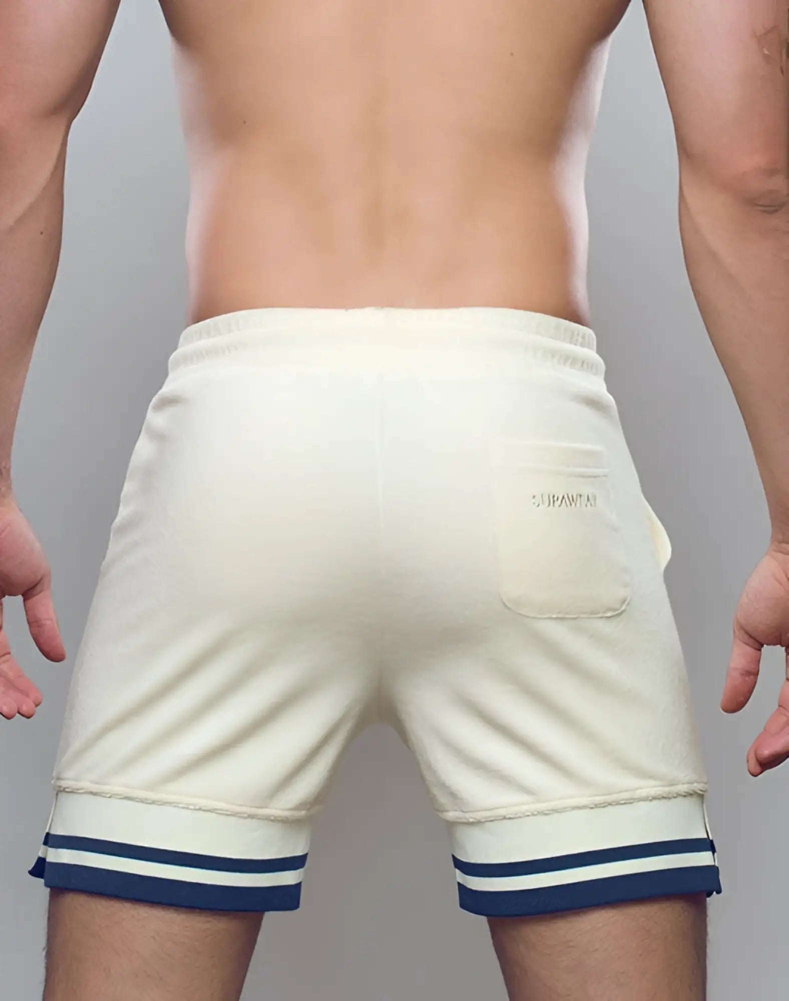 Cream-colored SUPAWEAR terry towelling shorts with navy white striped cuffs and branded patch on back pocket
