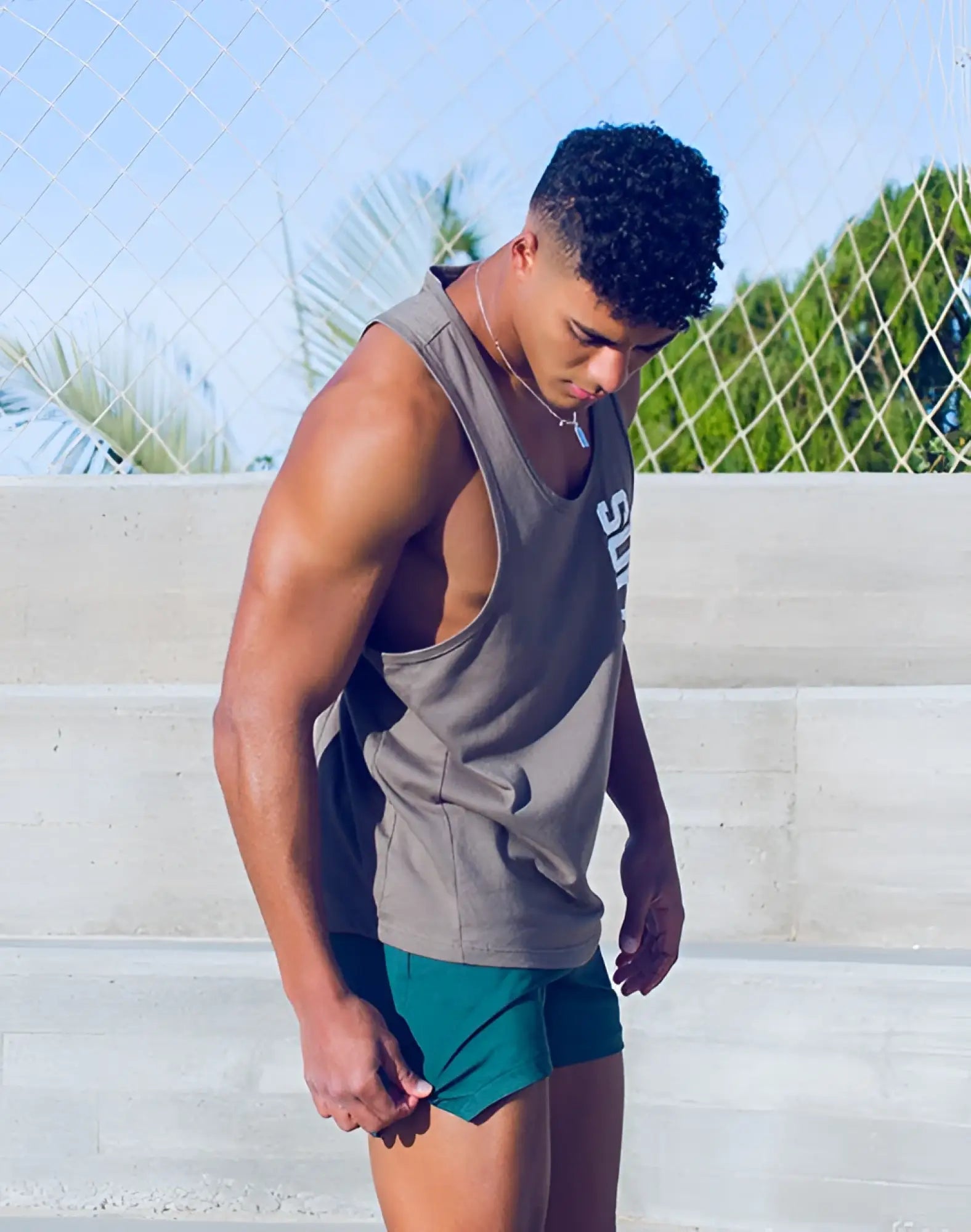 Gray sleeveless athletic tank top with v-neck and white lettering paired with supawear nexus dark green training shorts