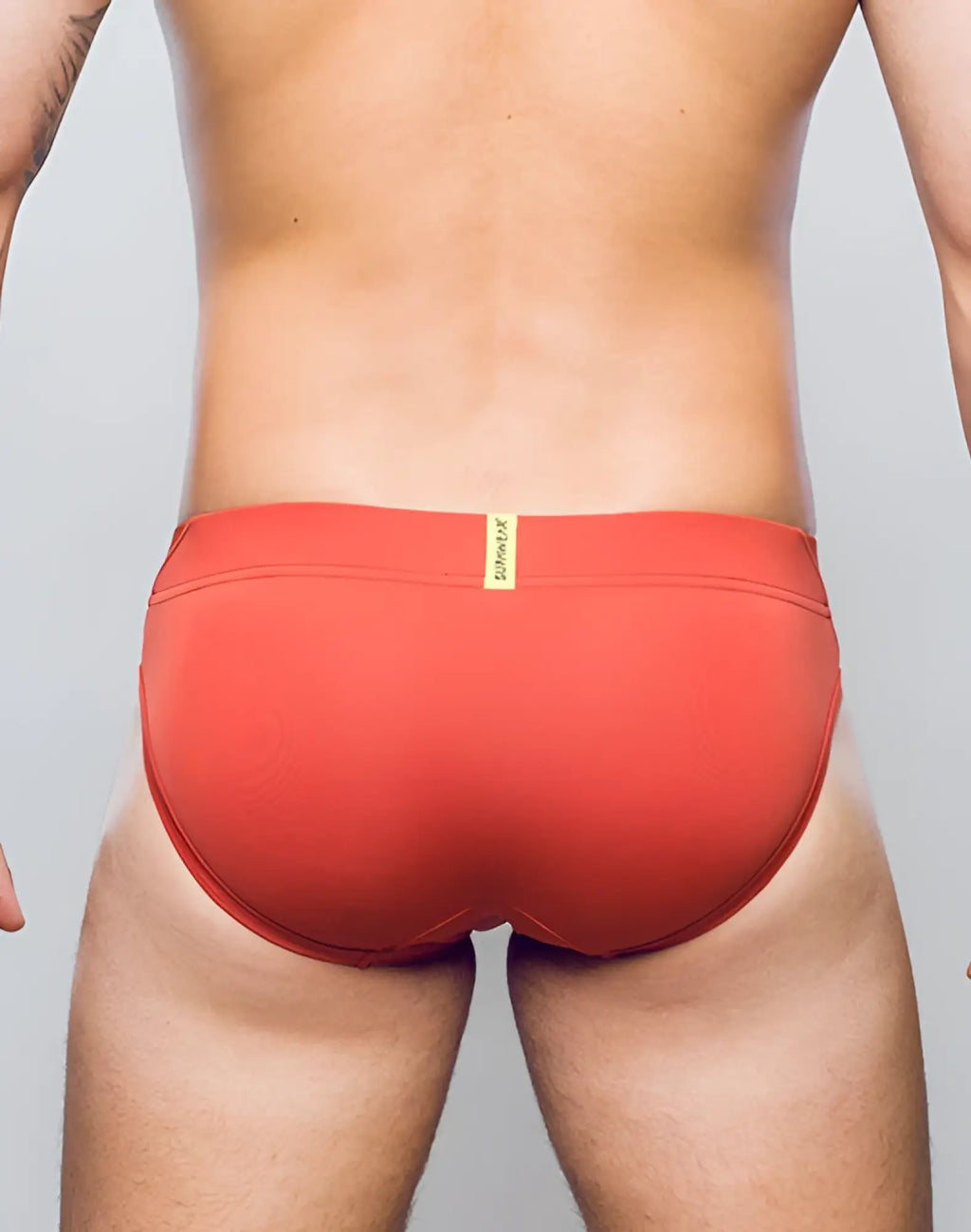Red swim trunks cranberry vortex brief underwear with yellow brand tag at waistband by supawear