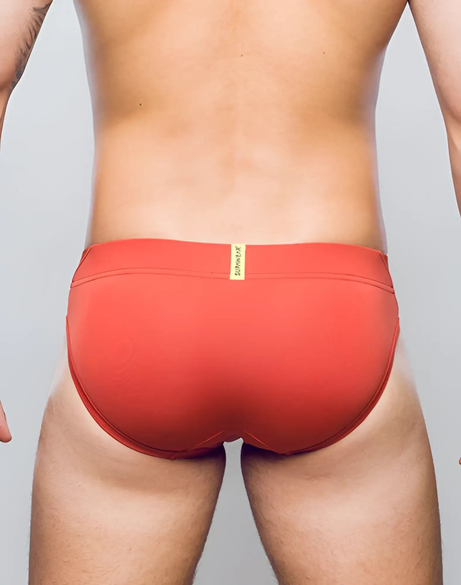 Red swim trunks cranberry vortex brief underwear with yellow brand tag at waistband by supawear