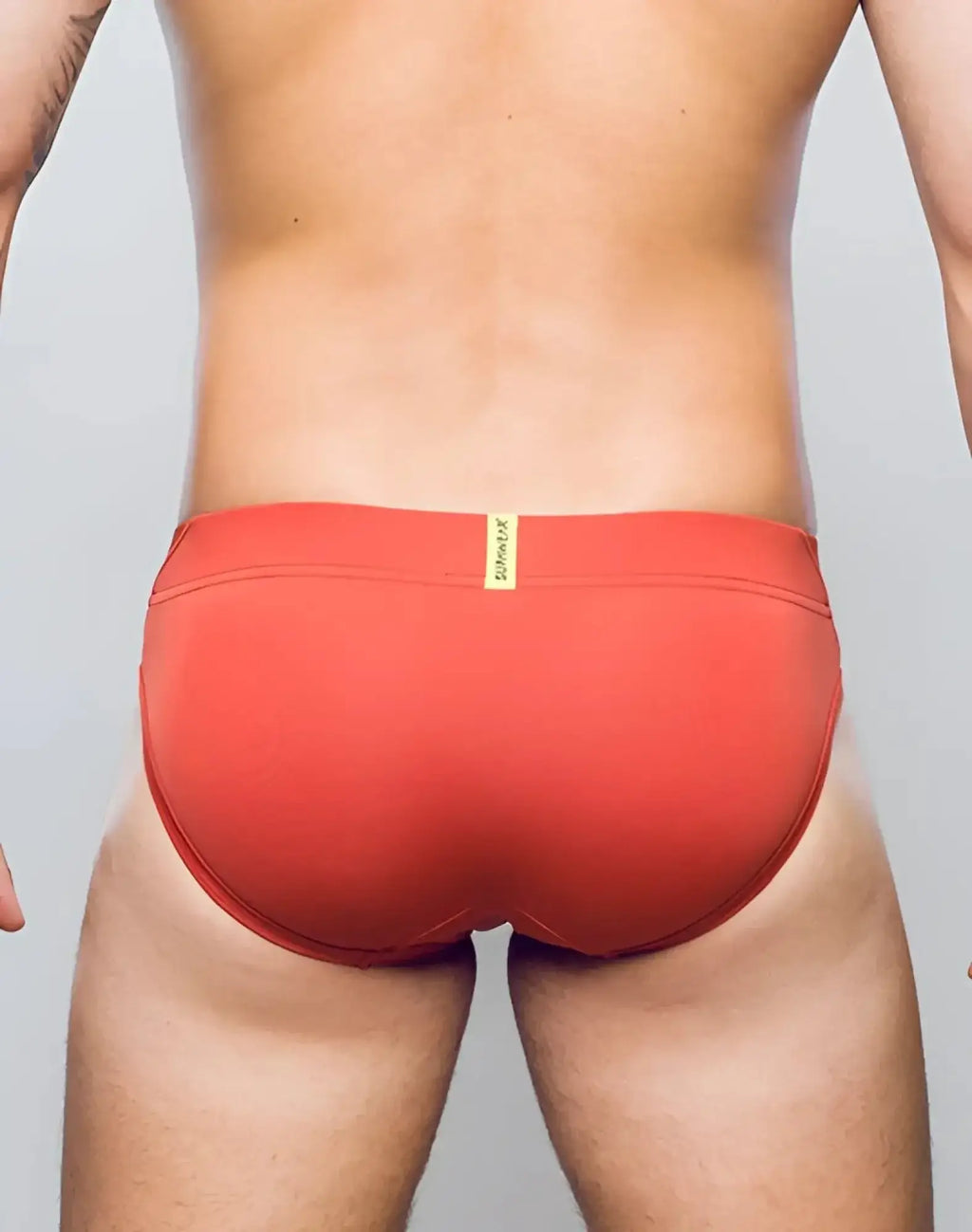 Red swim trunks cranberry vortex brief underwear with yellow brand tag at waistband by supawear