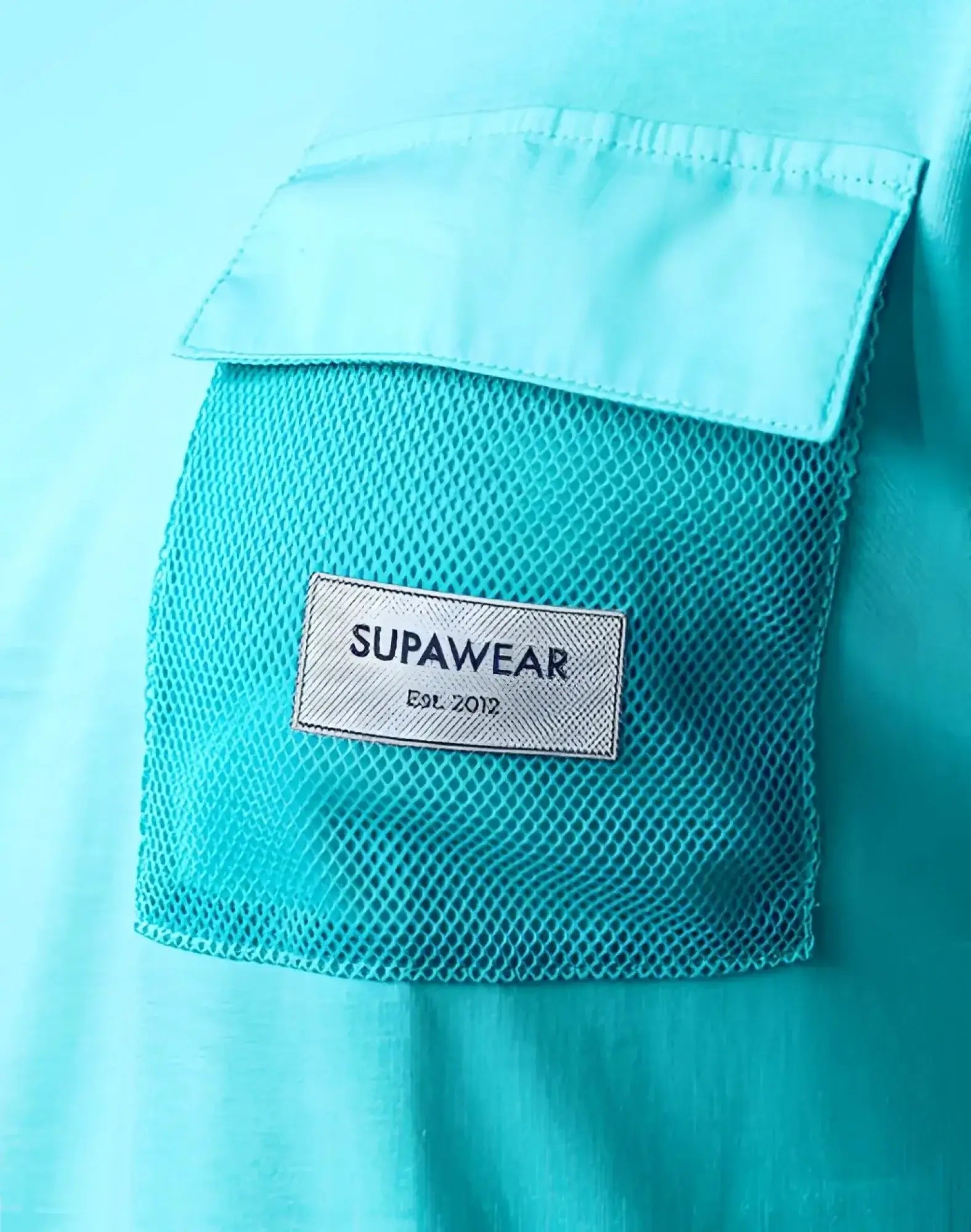 A turquoise blue supawear wide cut tank with a white mesh pocket and supawear label