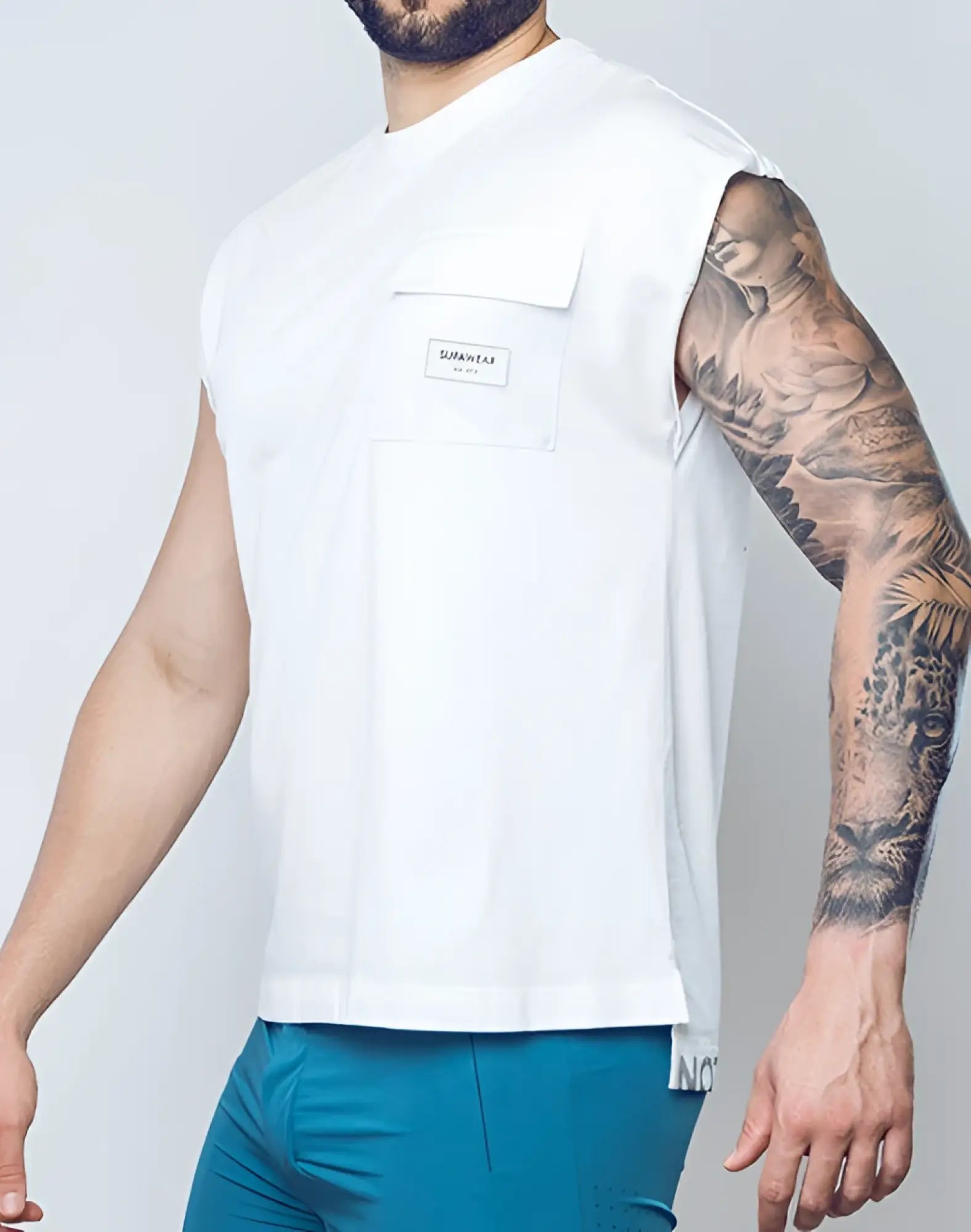 SupaWear wide-cut white sleeveless tank with chest pocket and small rectangular brand label on lightweight fabric