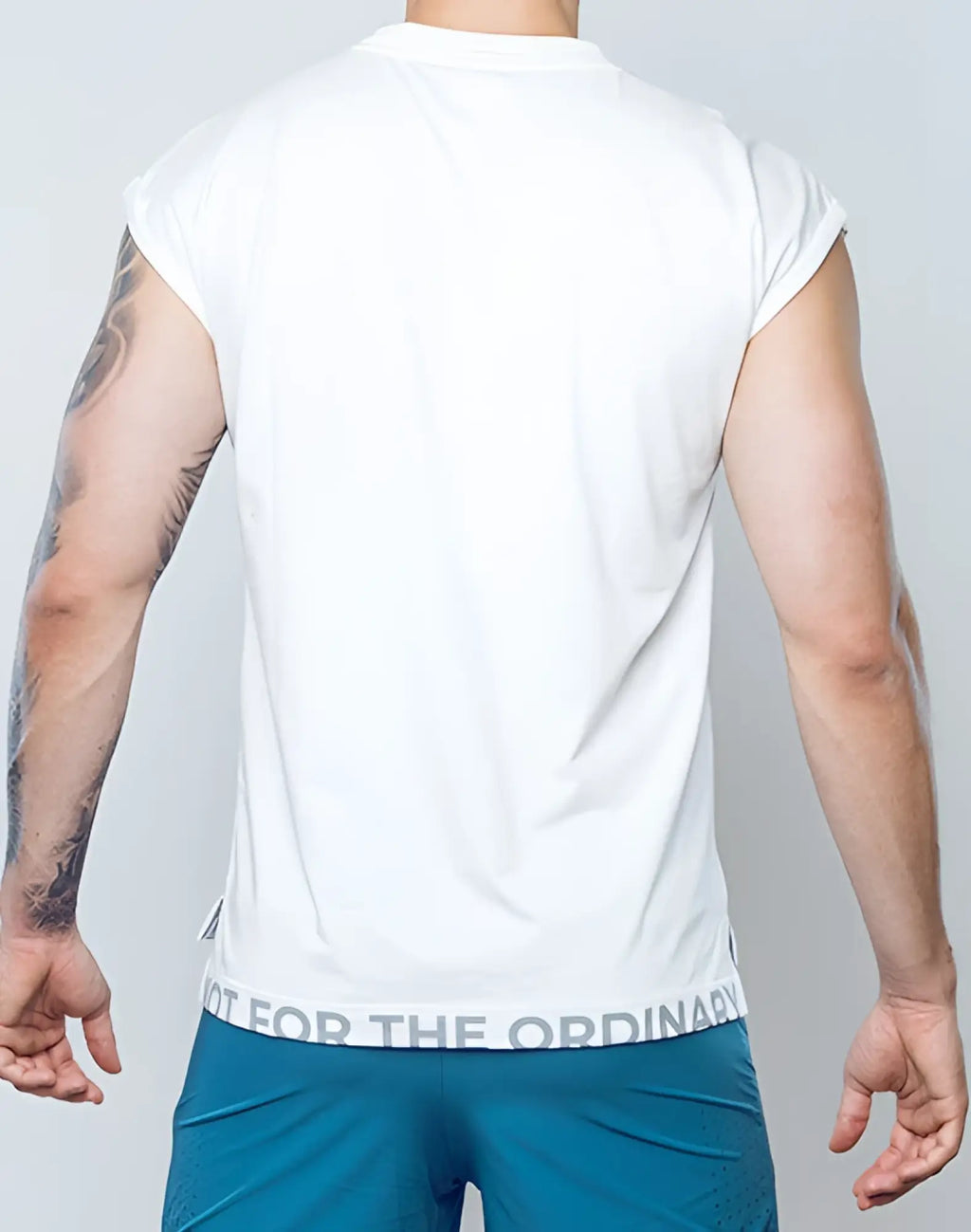 White sleeveless SUPAWEAR wide-cut tank with a subtle gray text band at the hem reading not for the ordinary