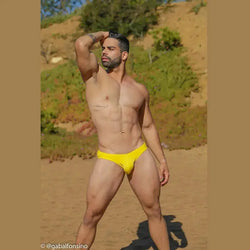 Men's yellow bikini swimwear by Arroyman featuring a snug fit and minimal coverage modeled on a beach.