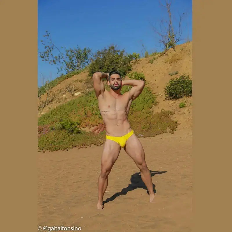 Men's yellow bikini swimwear by Arroyman featuring a snug fit worn by a model on a sandy beach.