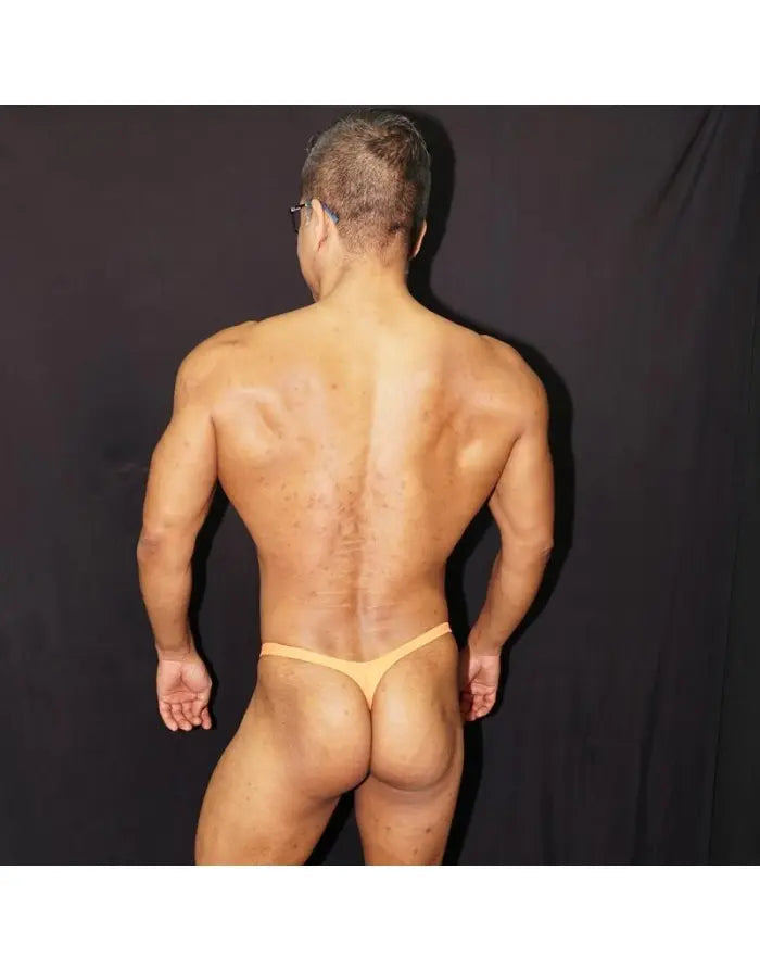 Model wearing Arroyman orange thong underwear showcasing a minimal back design and smooth fabric.