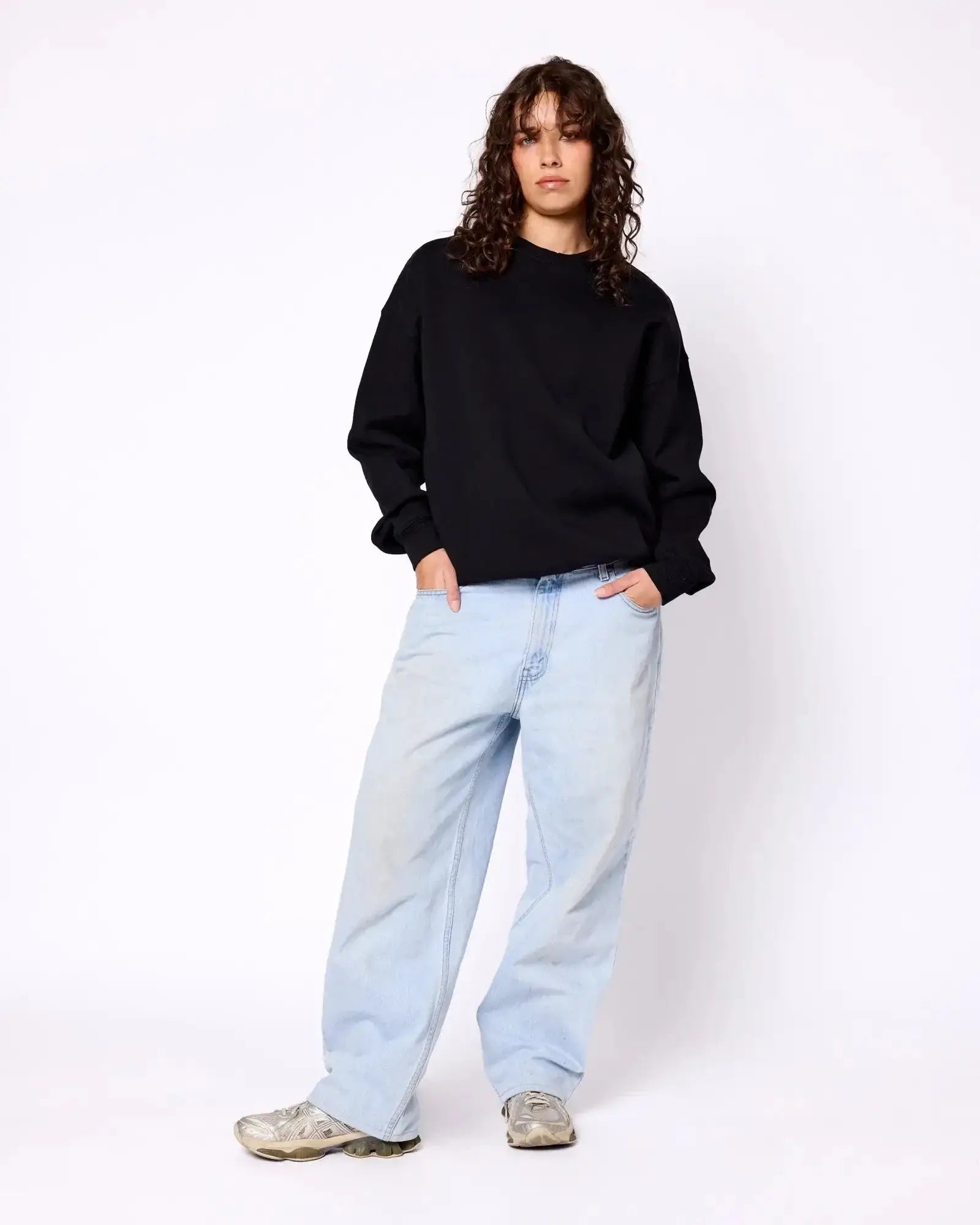 Model wearing a relaxed, black long-sleeve crewneck sweatshirt with dropped shoulders and ribbed cuffs.