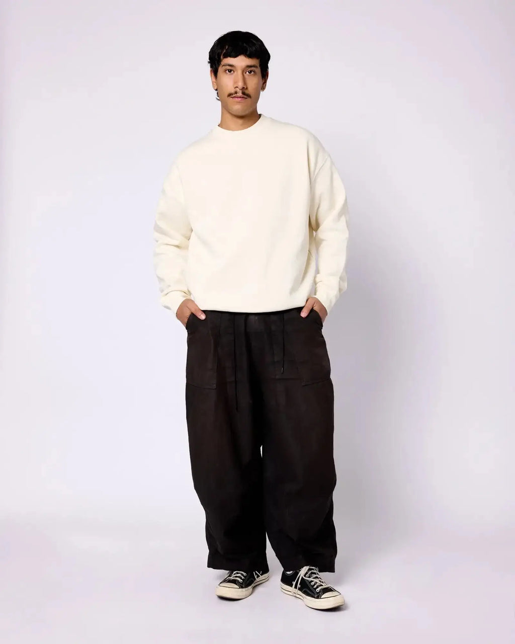 Model wearing an off-white, long-sleeve crewneck sweatshirt with a relaxed fit and dropped shoulders.