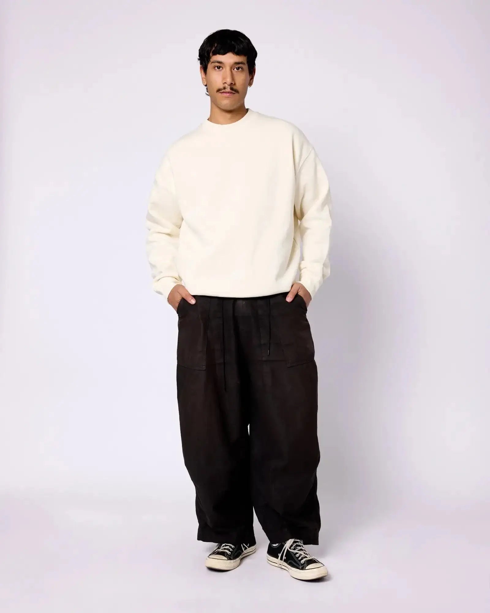 Model wearing an off-white, long-sleeve crewneck sweatshirt with a relaxed fit and dropped shoulders.