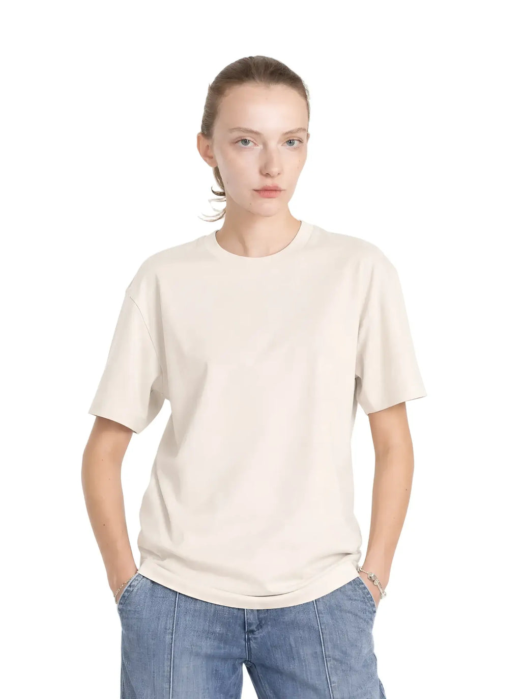Model wears a cream-colored, relaxed-fit cotton core tee with a classic crew neck and short sleeves.