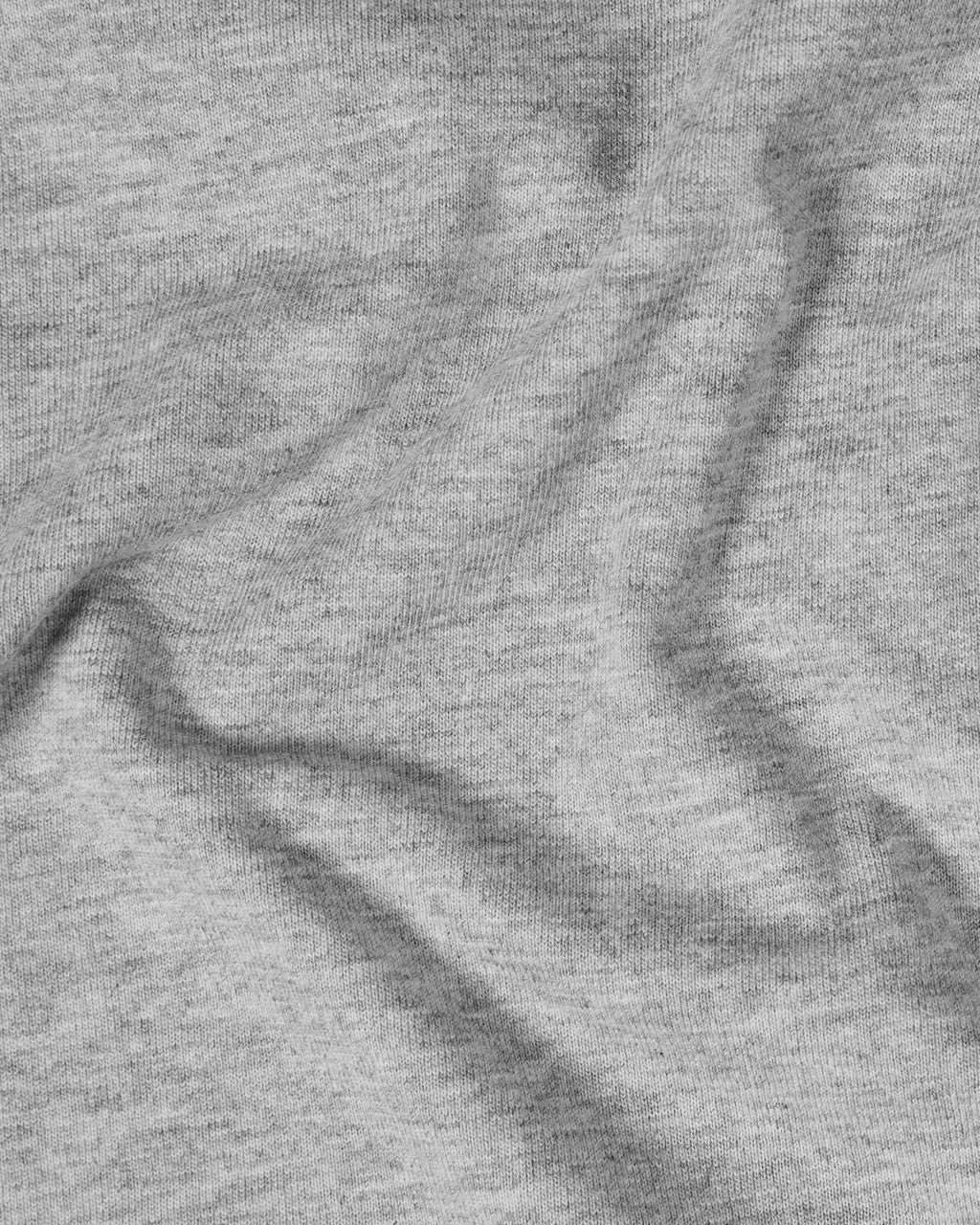 Close-up of a soft grey heather jersey t-shirt fabric with natural folds and a subtle, textured knit finish.