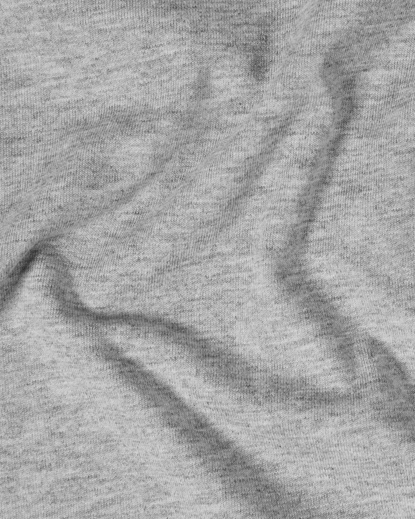 Close-up of a soft grey heather jersey t-shirt fabric with natural folds and a subtle, textured knit finish.