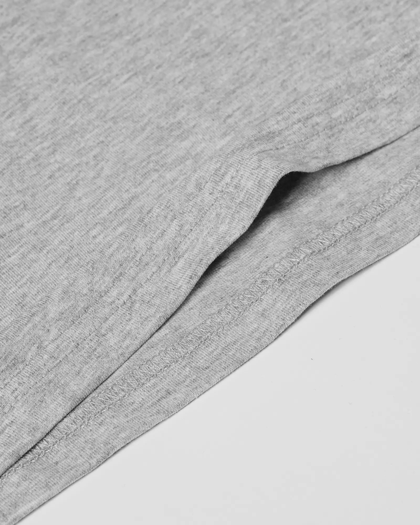 Close-up of a heather grey Core Tee showing the soft fabric texture and double-stitched hem detail.