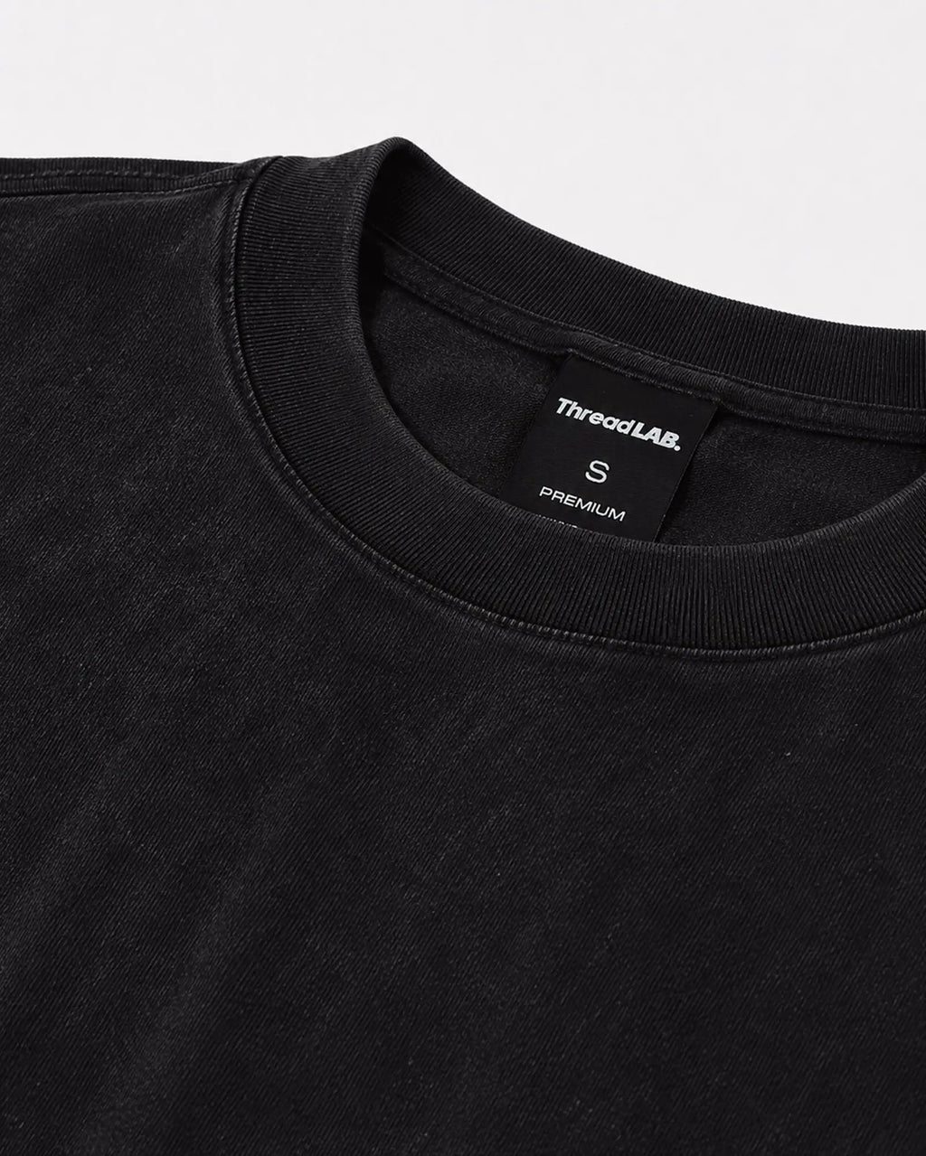 Close-up of a black crew-neck premium t-shirt with a ribbed collar and ThreadLAB size small tag.
