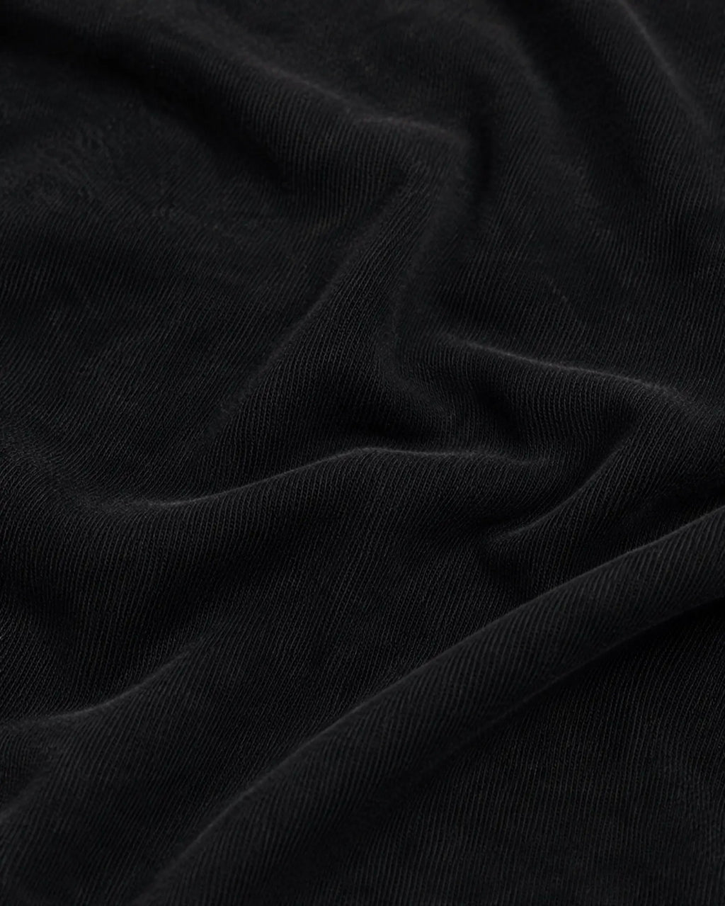 Close-up of soft, matte black fabric with visible fine-knit texture and elegant folds.